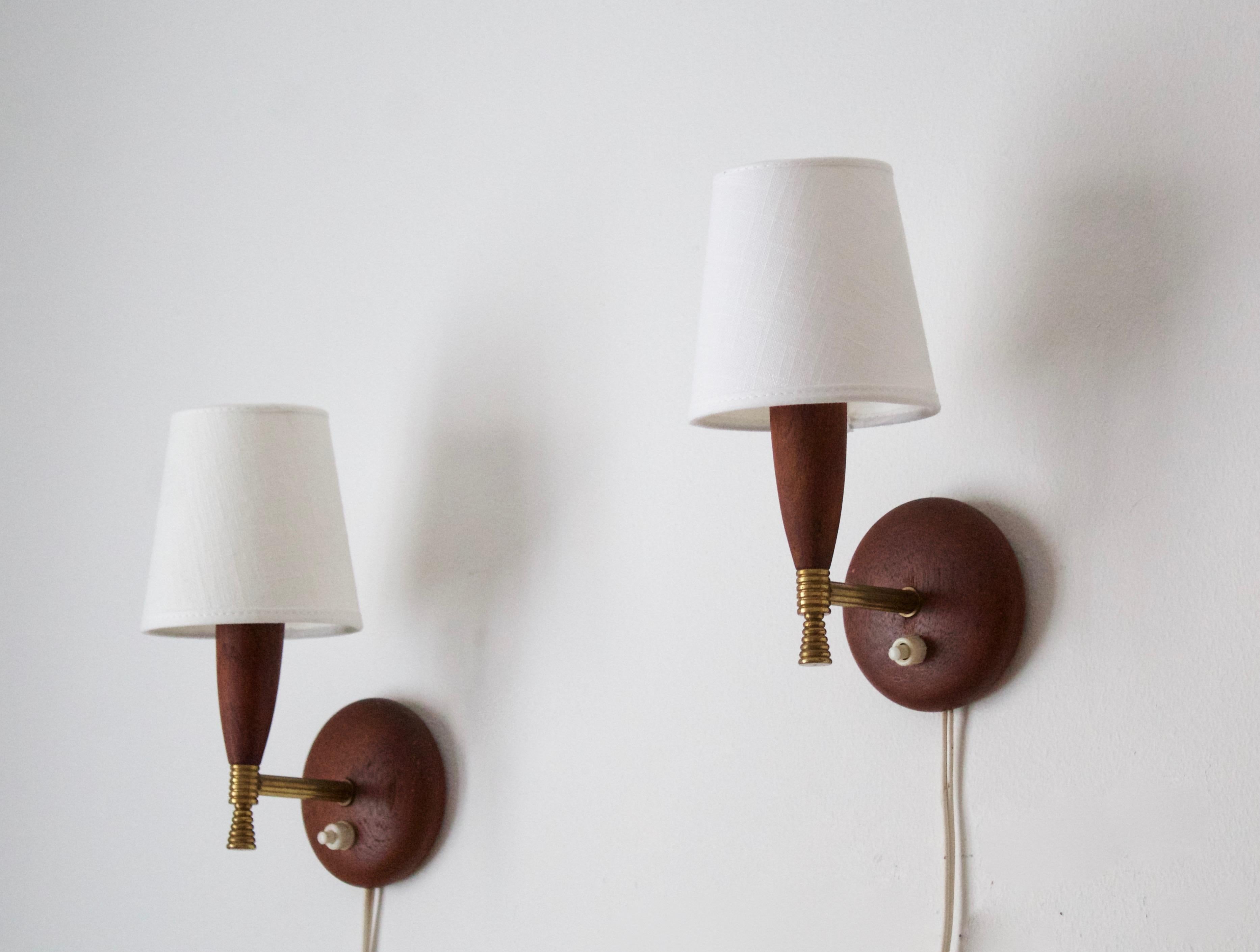 A pair of small wall lights / wall sconces. Designed and produced in Denmark, 1950s. Brand new linen lampshades.

Stated dimensions are measured with illustrated lampshades attached.

 