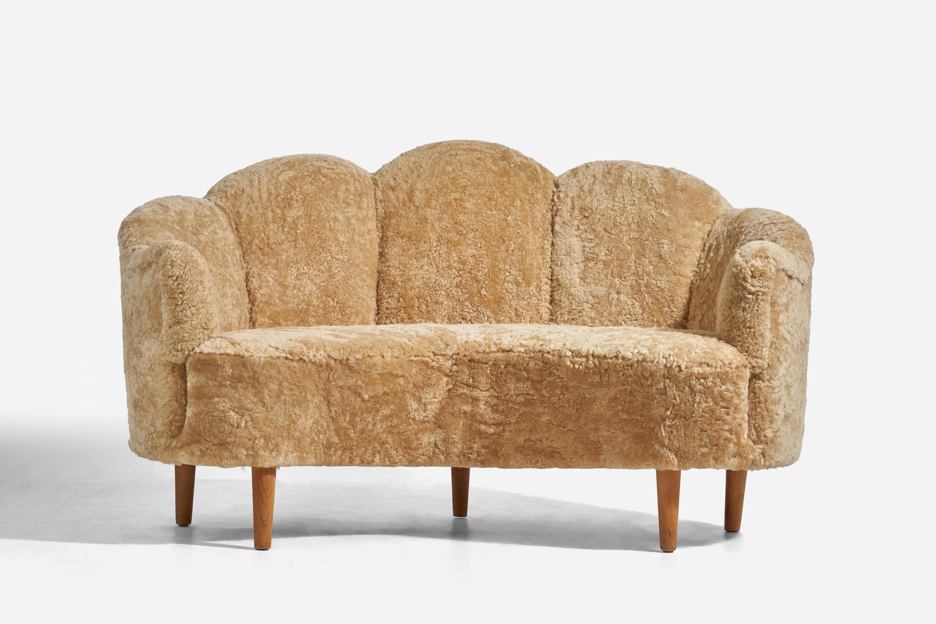 A sheepskin and wood sofa designed and produced in Denmark, c. 1940s.