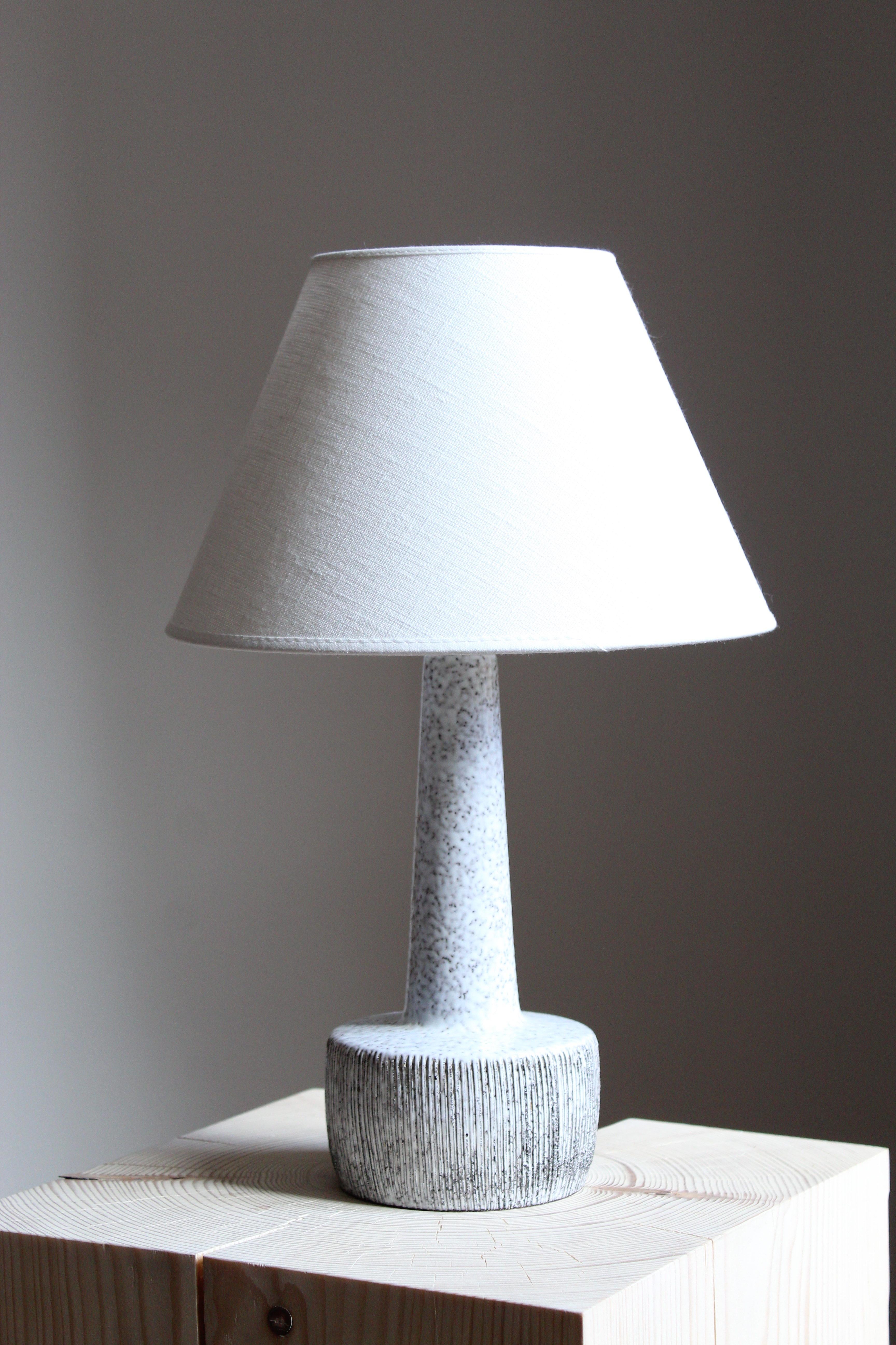 A table lamp. Designed and produced by unknown designer / studio potter. Denmark 1960s. Unsigned. Lampshade not included.

Glaze features a white color with hints of brown.