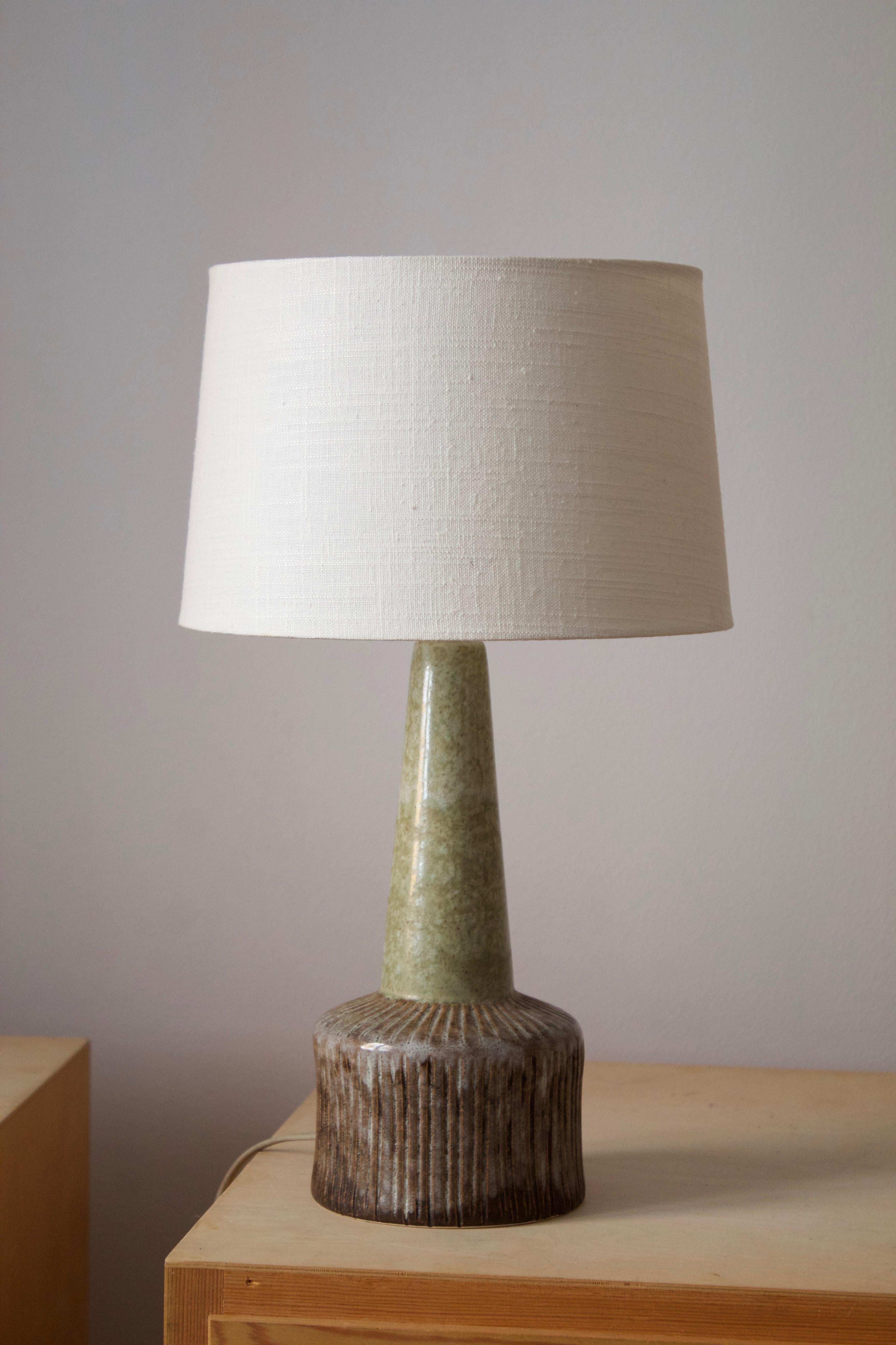 A small table lamp. Signed. Designed and produced in Denmark, 1960s. Unidentified designer and maker. Brand new high-end linen lampshade.

Sold without lampshade, stated dimensions excludes lampshade. 

Glaze features brown-green colors.

Other