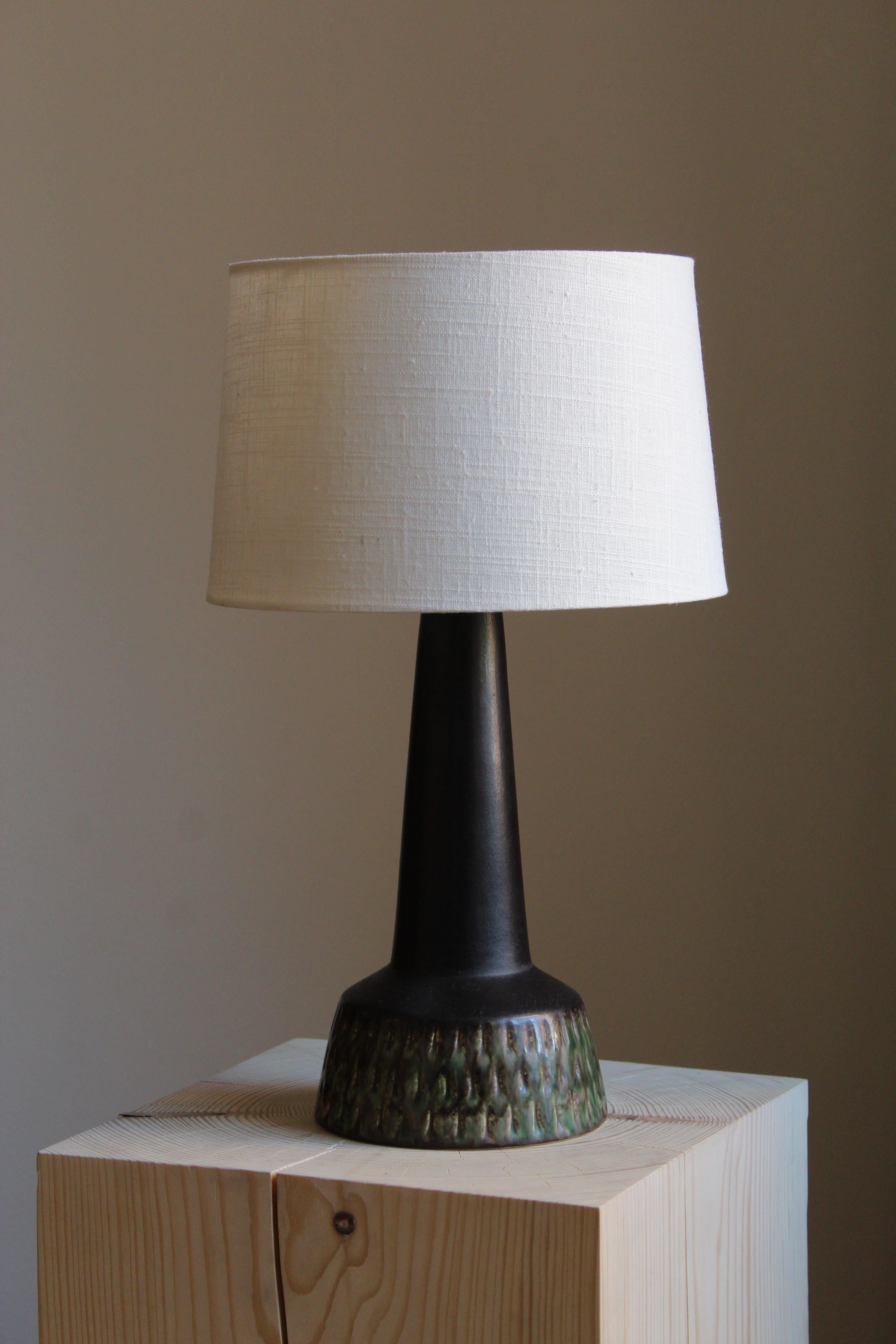A modernist table lamp. Designed and produced in Denmark, 1960s. Unsigned. 

Sold without lampshade.

Glaze features black-green colors.

Other designers of the period include Axel Salto, Arne Bang, Carl-Harry Stålhane, Gunnar Nylund and Wilhelm