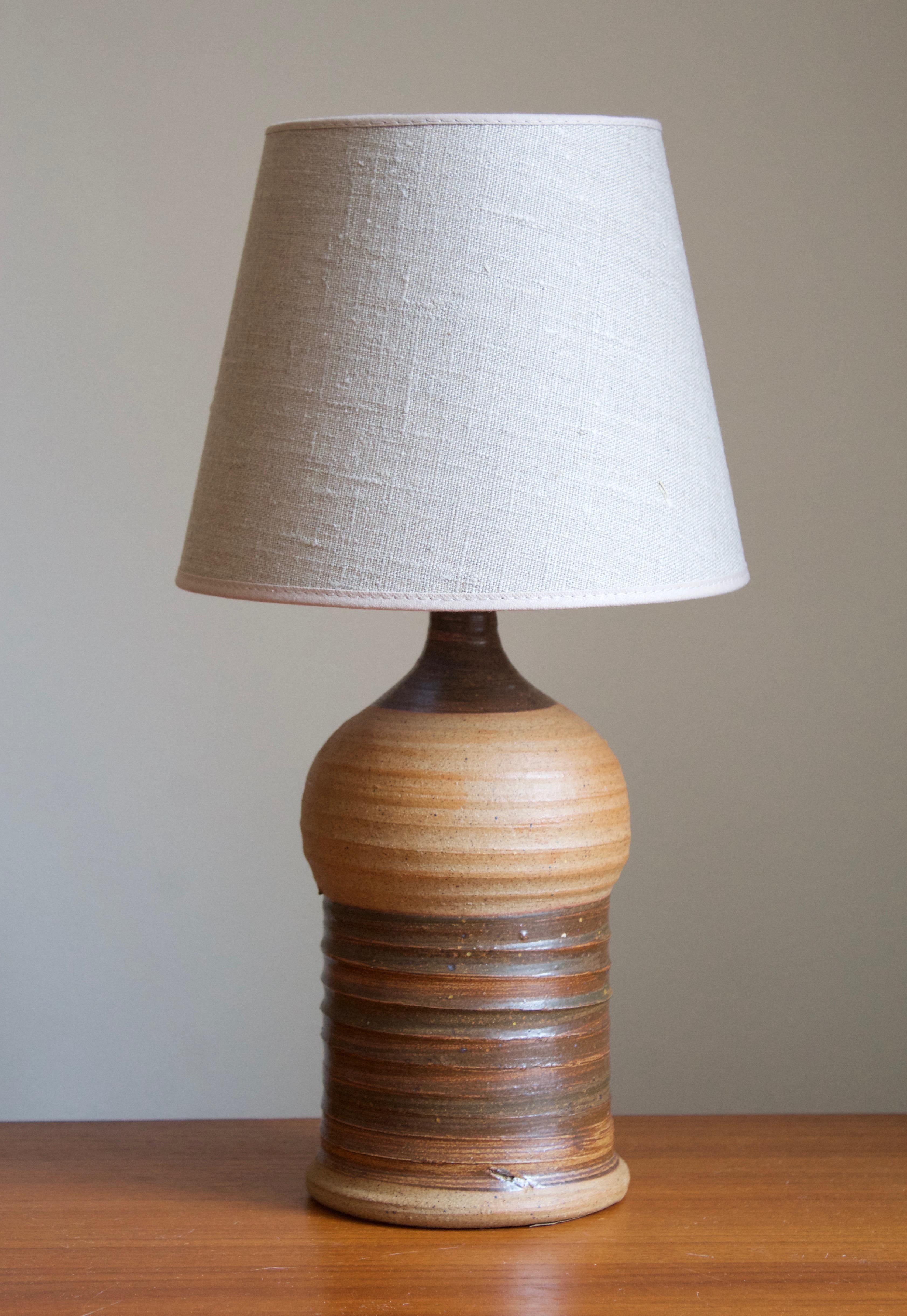 A small table lamp. Signed. Designed and produced in Denmark, 1960s. Unidentified designer and maker. 

Stated dimensions excludes lampshade. Height includes socket. Sold without lampshade.

Glaze features a brown color.

Other designers and makers