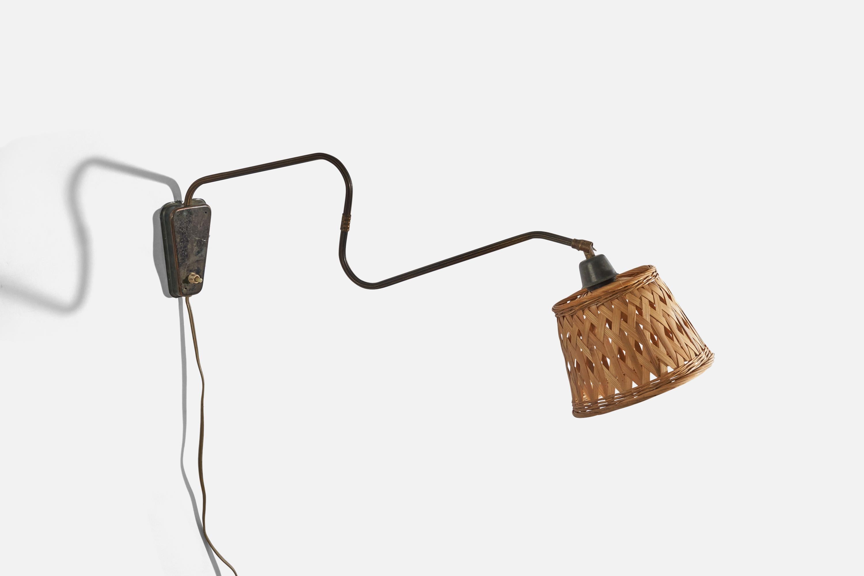 A brass and rattan wall light designed and produced in Denmark, 1940s. 

Sold with Lampshade. 
Stated dimensions refer to the lamp with the lampshade.
Variable dimensions, measured as illustrated in the first image. 
Dimensions of back plate