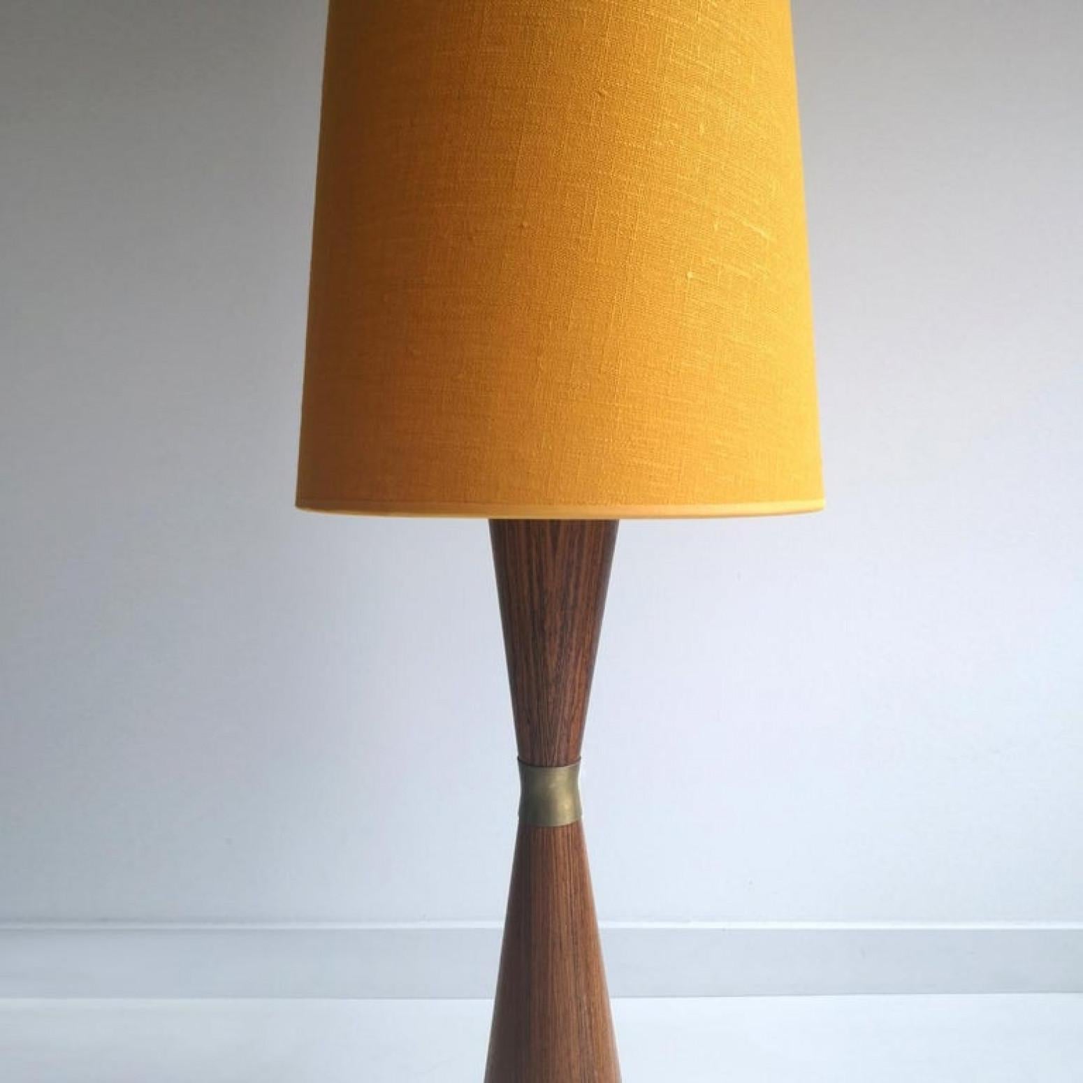 Esta rara lámpara de pie diablo de teca moderna fue diseñada en los años sesenta. La base está lastrada para que sea resistente. Muy elegante e inusual. En el centro hay un brazalete de cobre. La nueva pantalla de lino tapizada proporciona un cálido