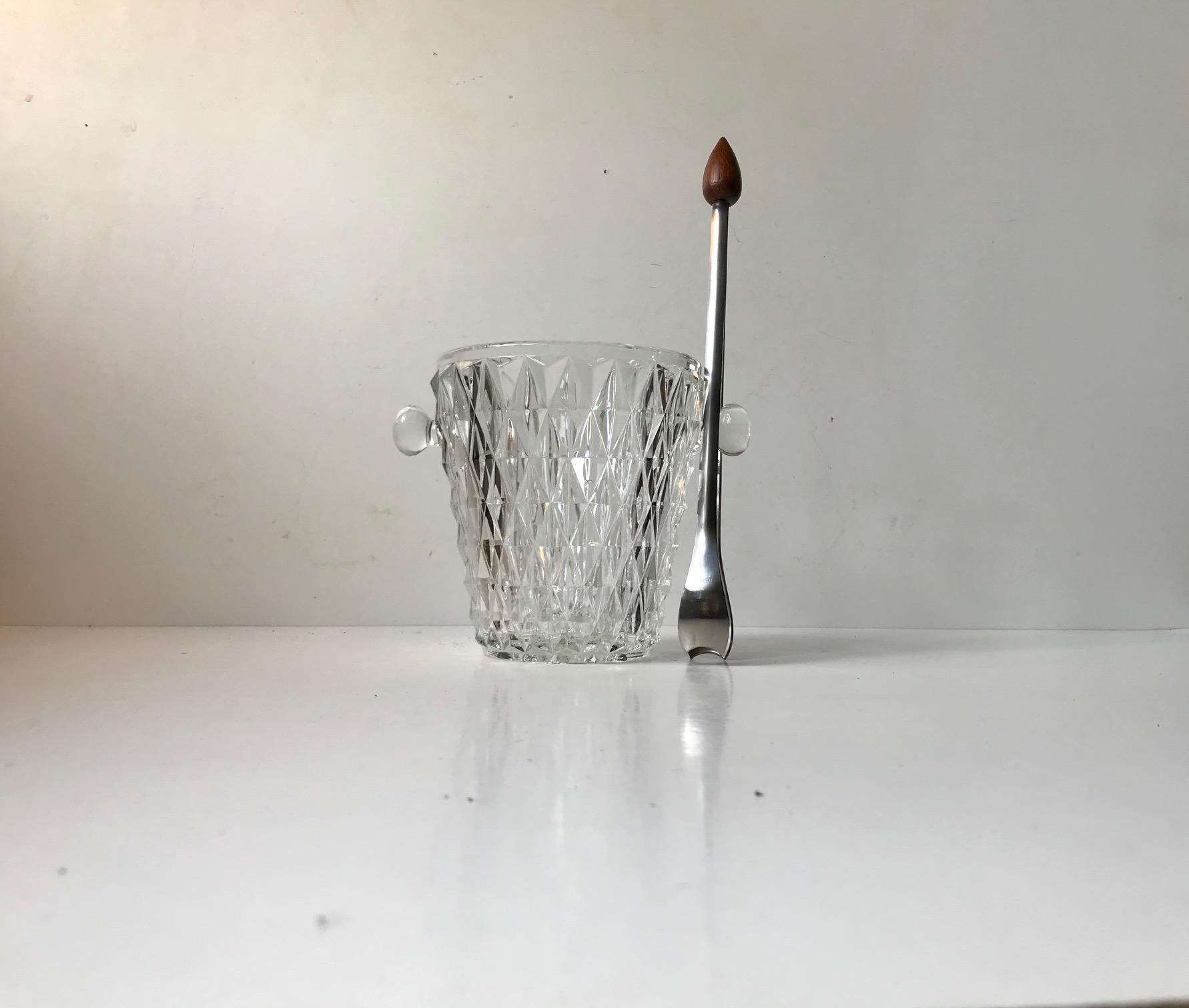 A pressed glass ice bucket and a stainless steel tong with teak knob/handle. Both in excellent condition and both manufactured in Denmark during the 1960s.