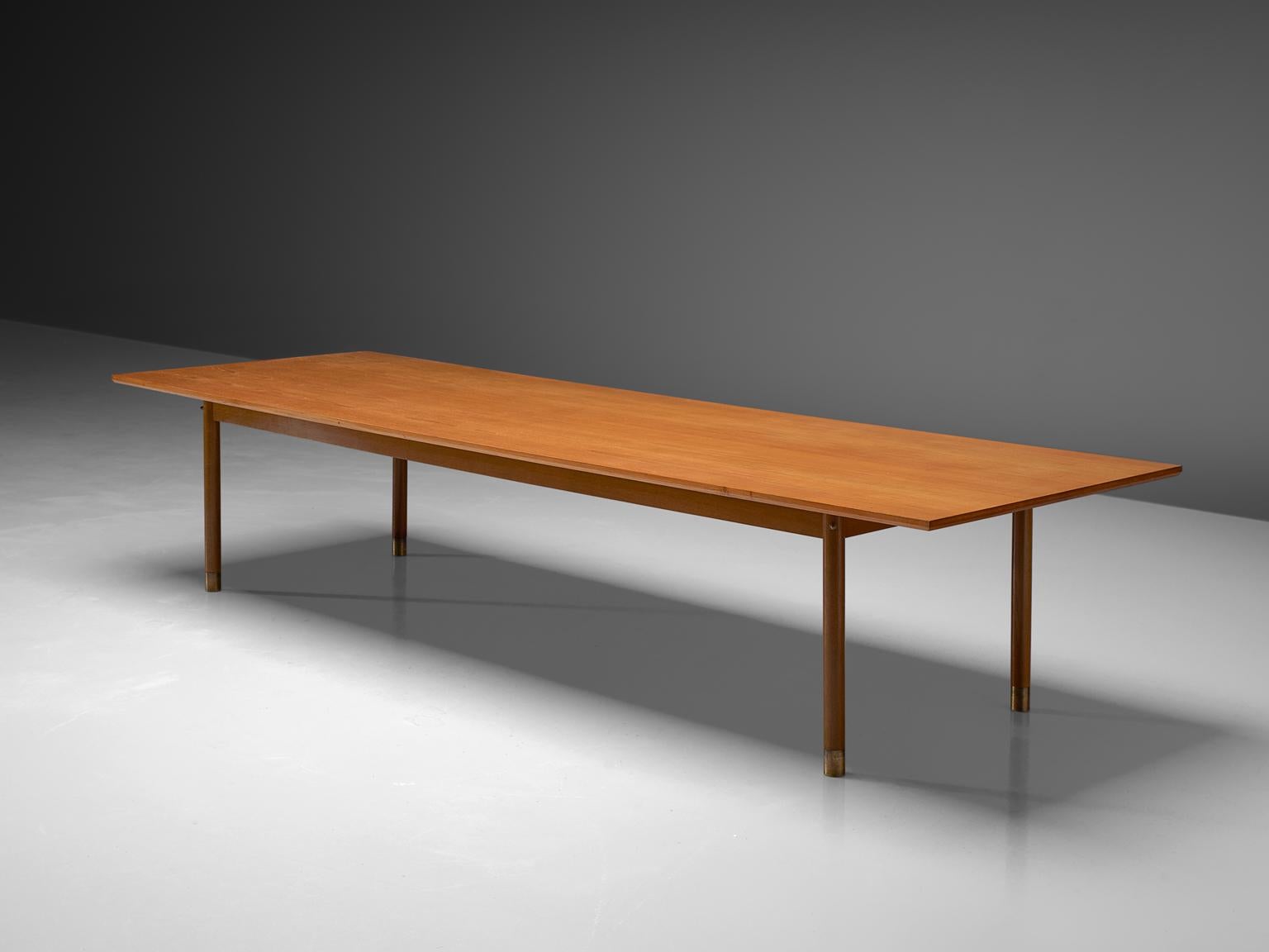 Danish dining or conference table, teak, brass, Denmark, 1950s

A rectangular top is lifted up by four circular legs with brass feet. The large top reaches over the legs. The natural grain of the teak structures the top visually.


