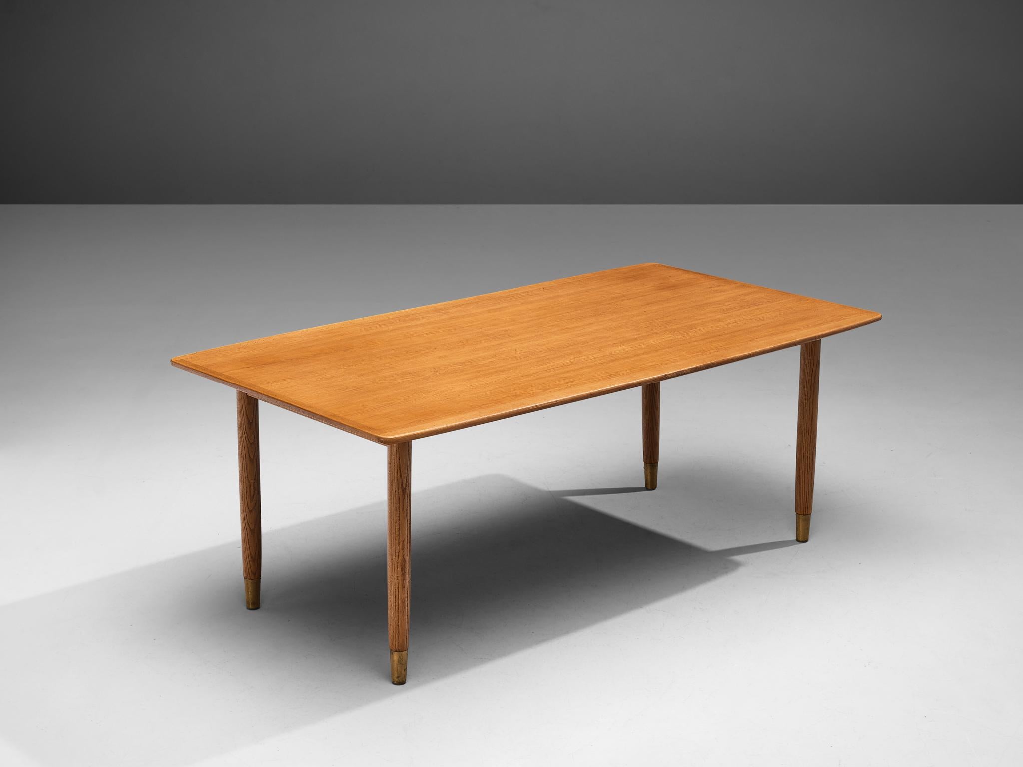 Dining table, oak, brass, Denmark, 1950s

Scandinavian Modern dining table with rectangular top. The warm colored top rests on four circular, tapered legs that have brass feet. This detail gives the design strength and characterizes this table.
 