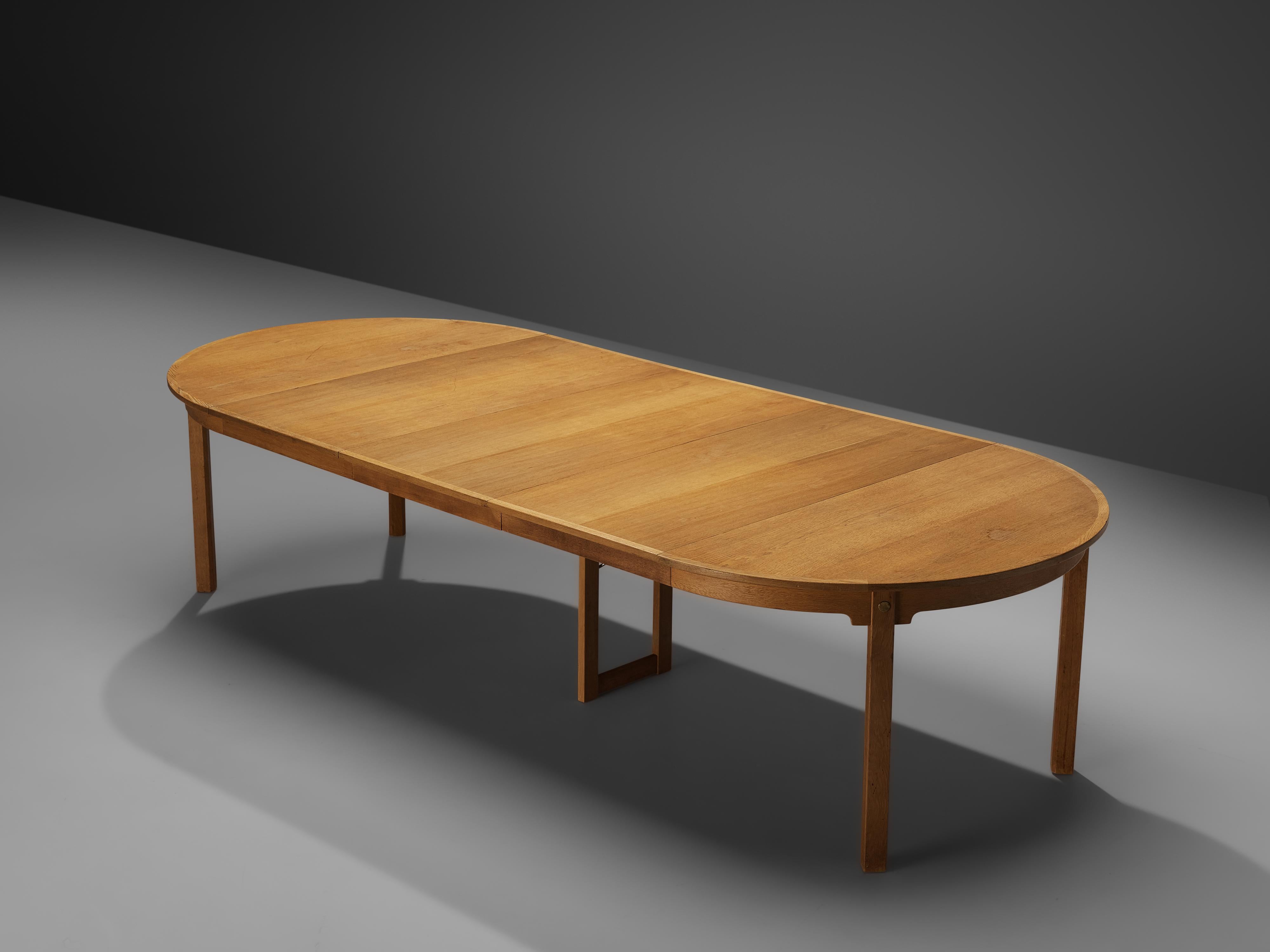Extendable dining table, oak, brass, Denmark, 1950s.

This dining table comes with three extra leaves that allow you to transform the small round table into a long oval dining table. The table than spans over 3m (118in.). The oakwood shows a vivid