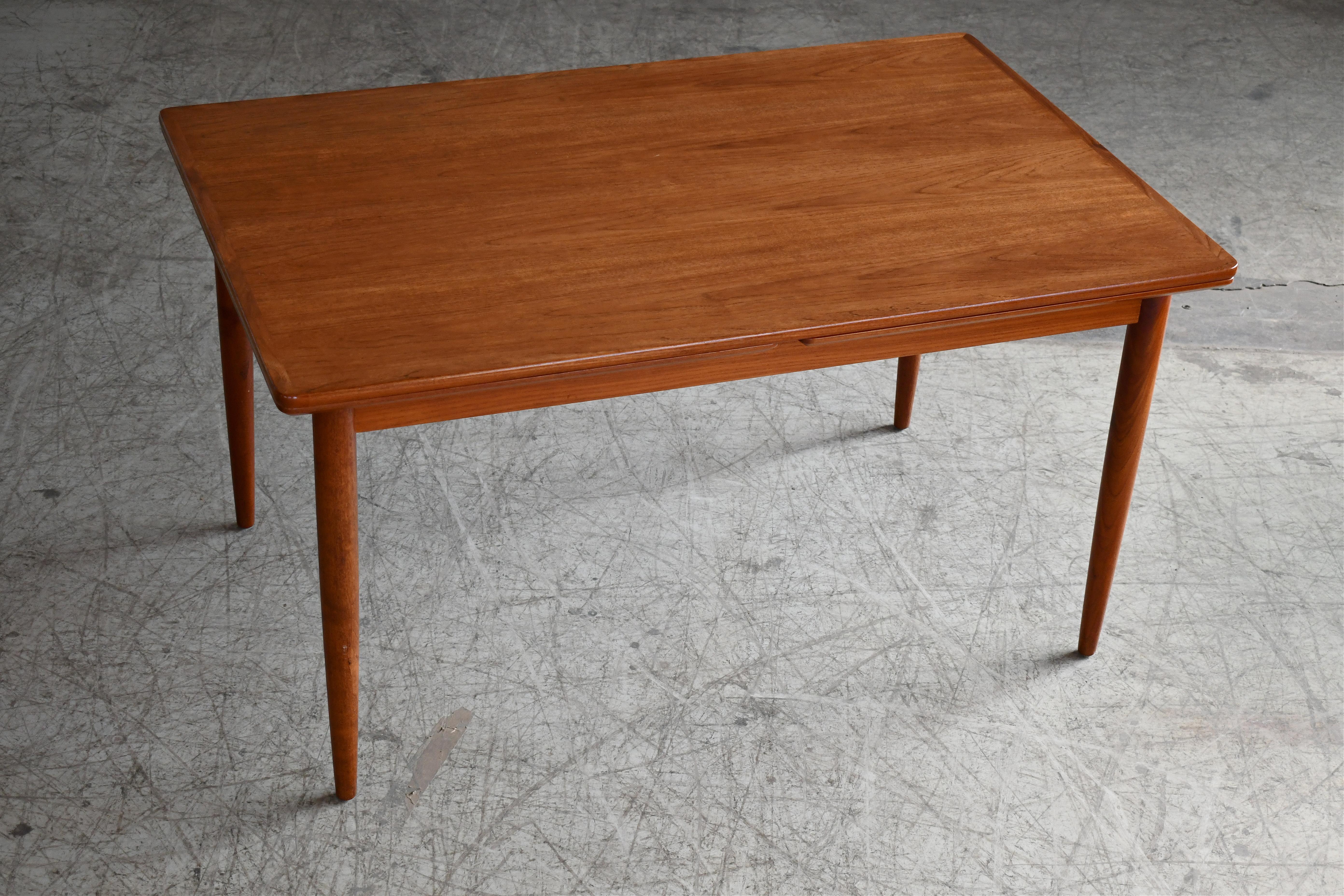 Very nice traditional Danish midcentury dining table with two pull-out leaves made sometime in the 1960's. Made from solid and veneered teak. Very good color and nice grain. Great condition with just very minor age wear. No large scratches of dings.