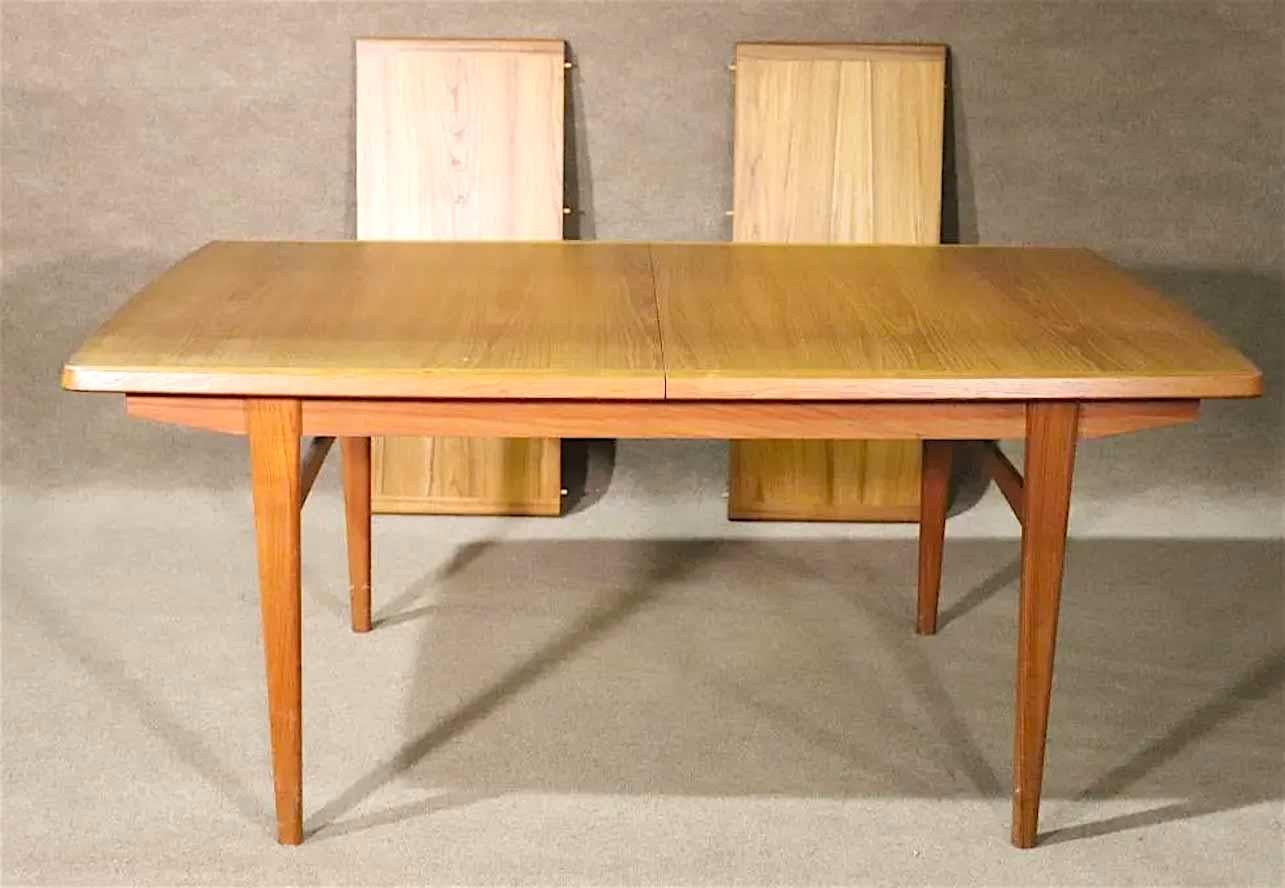 Mid-century modern teak dining table with leaves. Soft, simple design with curved edges and tapered legs. Each leaf is 19