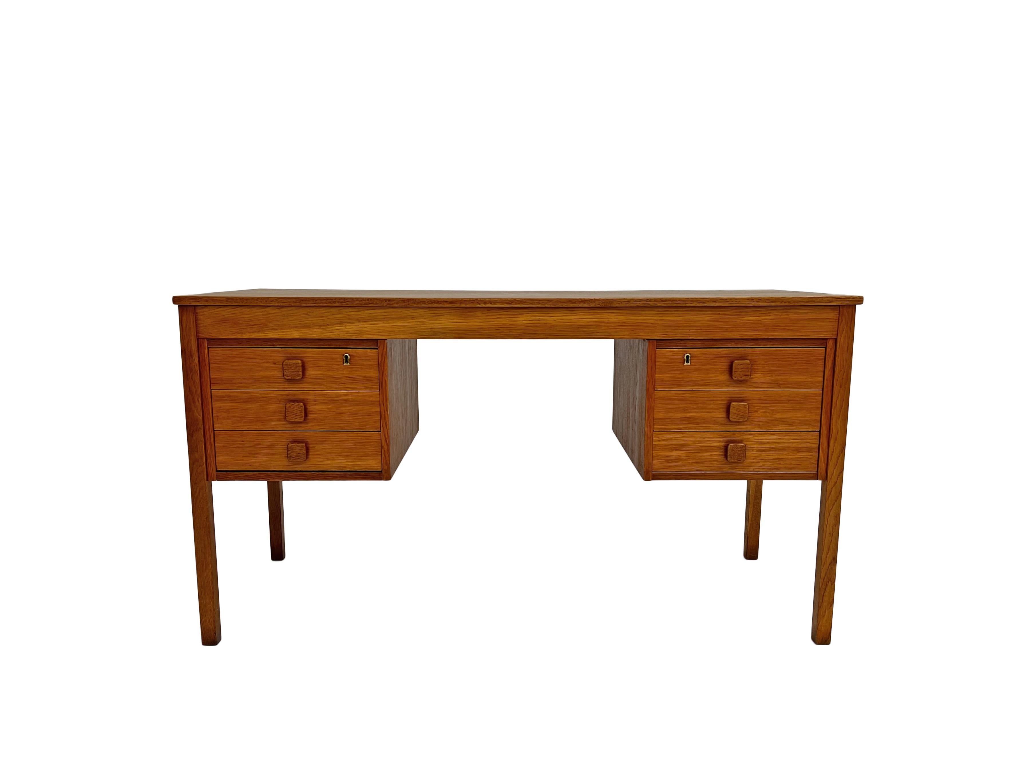 A beautiful Danish oak pedestal writing desk by Domino Møbler, this would make a stylish addition to any work area. A striking piece of classically designed Scandinavian furniture.

The desk has two banks of three drawers, all are in good order with
