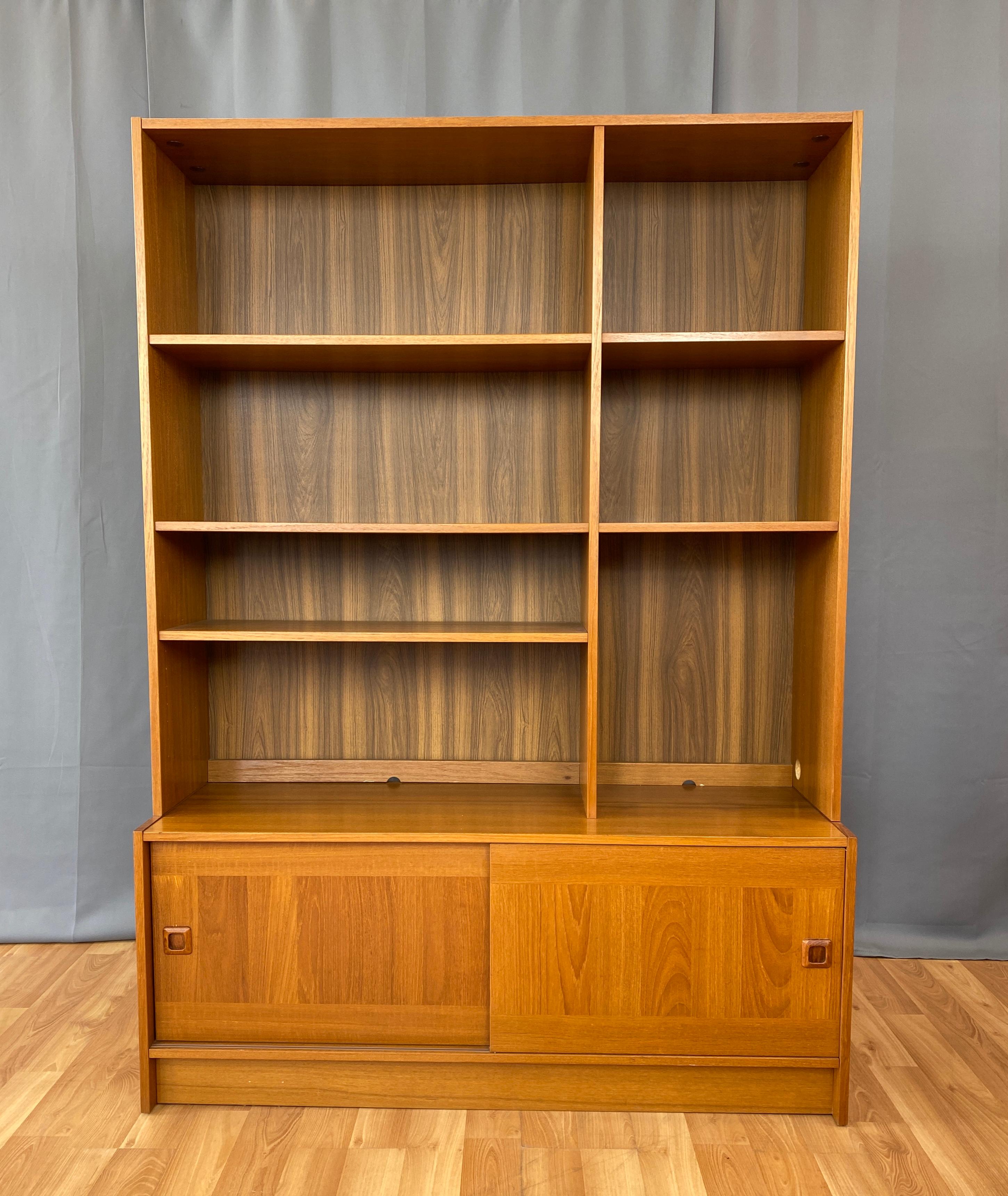 Offered here is a 1970s Danish teak credenza with a shelving unit sitting on top, made by Domino.
Credenza has two sliding doors, behind the doors ample storage. Sitting on top of the credenza is the shelving unit, with five shelves, three of them