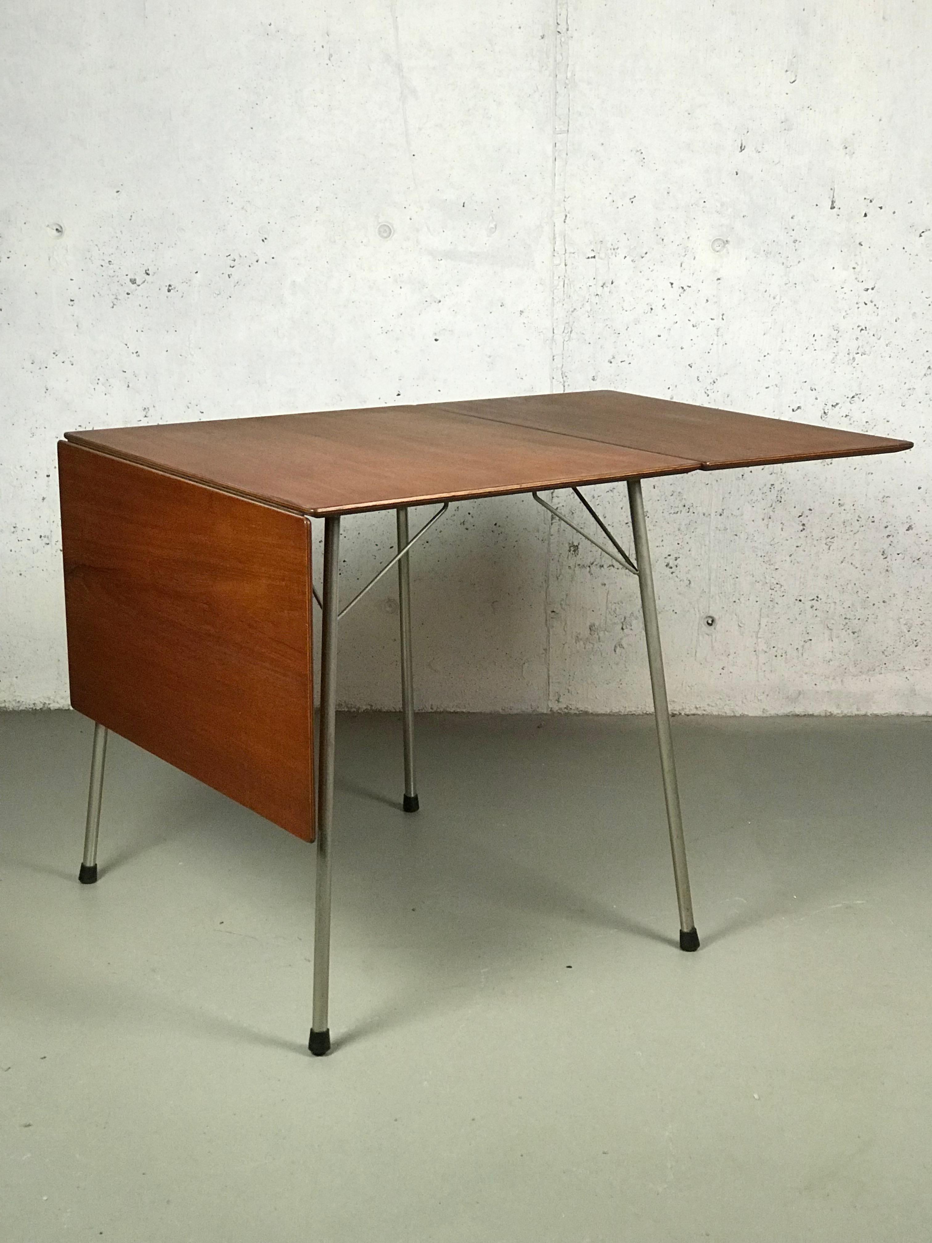 Sleek and petite Minimalist Danish teak drop-leaf dining table by Arne Jacobsen for Fritz Hansen; Model 3601. The top has been restored with a Danish oil finish. The legs have been cleaned but small spots of oxidation remain at the bottom of one leg