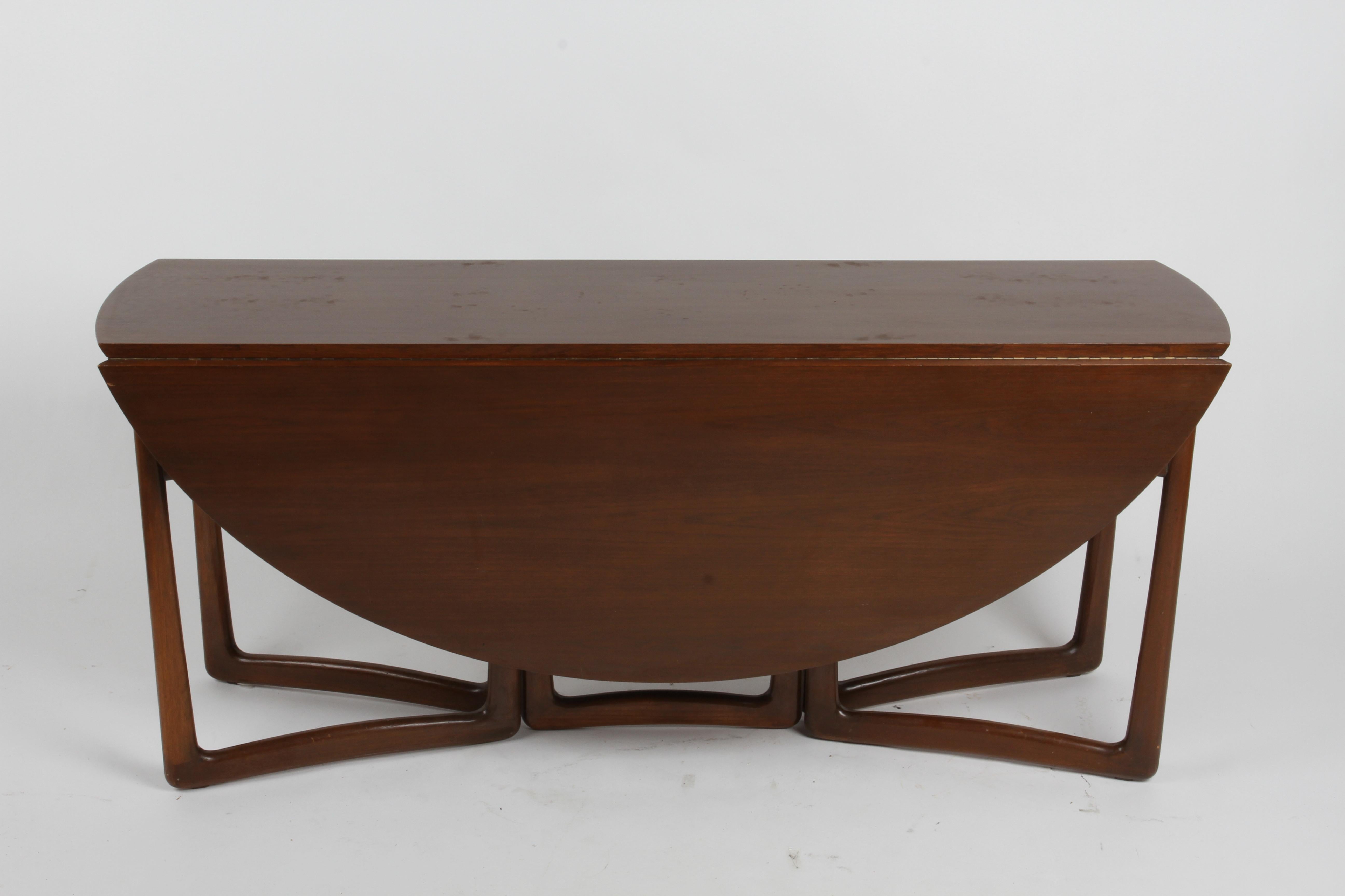 Beautiful 1960s teak drop-leaf table designed by Peter Hvidt and Orla Mølgaard Nielsen for France & Sons and imported by John Stuart Inc. The sculptural legs of this convertible table slide open easily to support the two drop leaves, and tuck in to