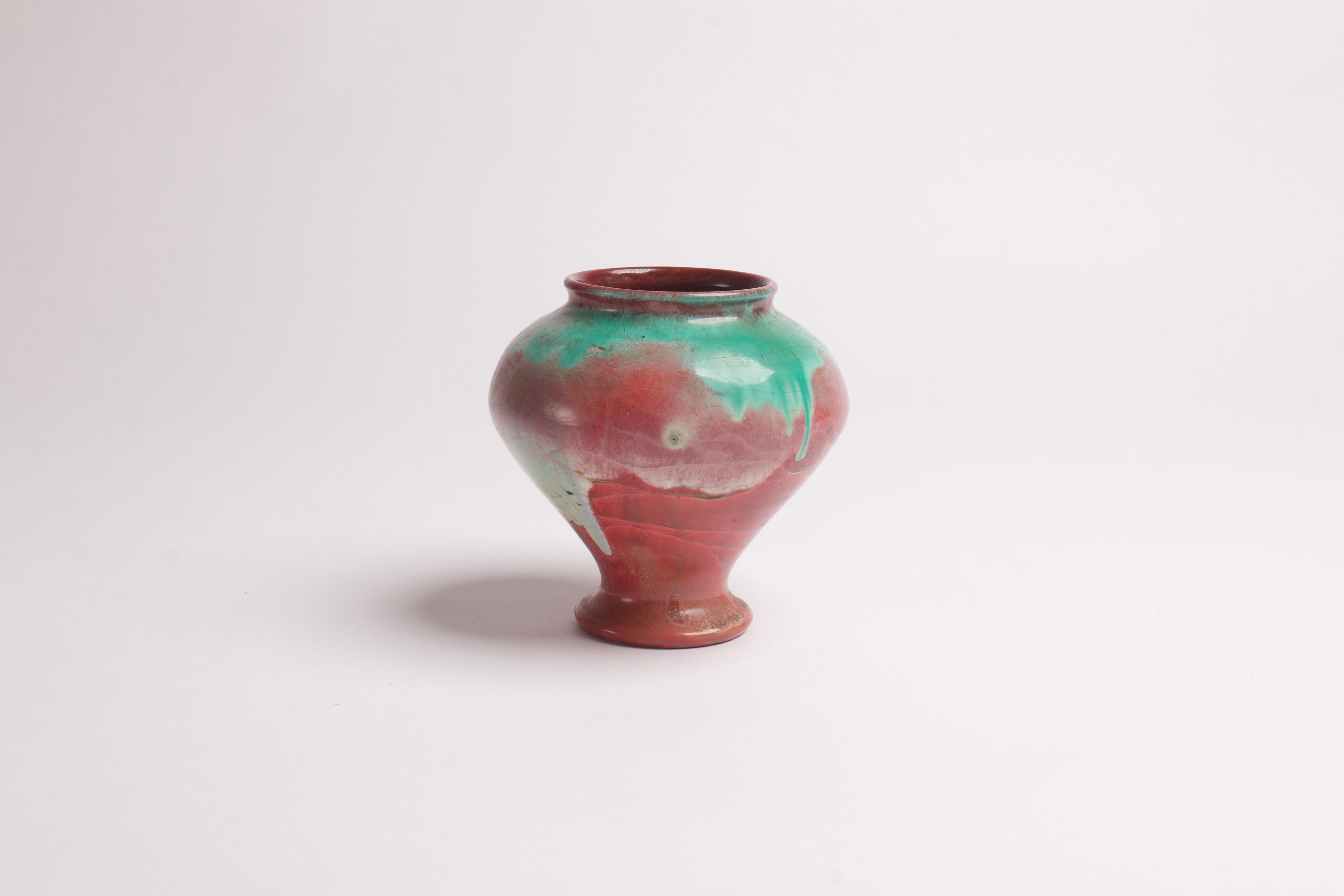 Cet élégant vase en faïence décoré d'une glaçure lustrée verte et rouge a été exécuté par Herman A. Kähler, poterie danoise, vers les années 1910.

Le vase porte le monogramme 