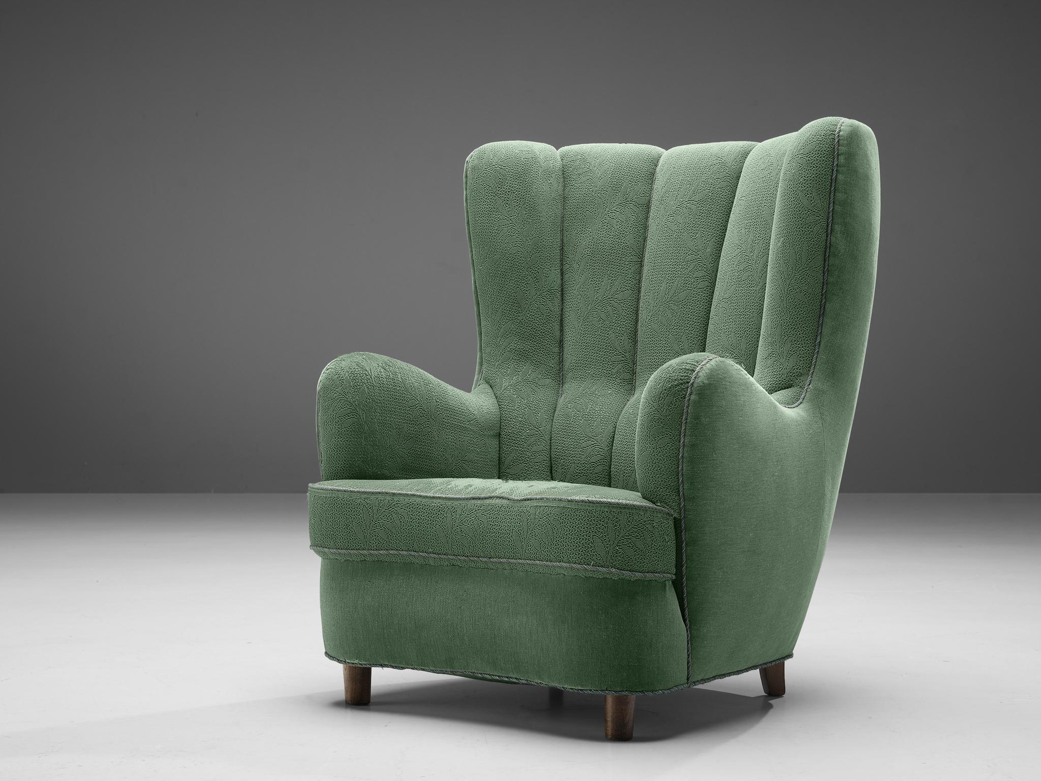 Easy chair, fabric, beech, Denmark, 1940s. 

This easy chair with its soft edges, tufted lines, and sturdy shape is typical for Danish design of the Art Deco period. The imposing, high backrest creates a comfortable experience, stimulating the