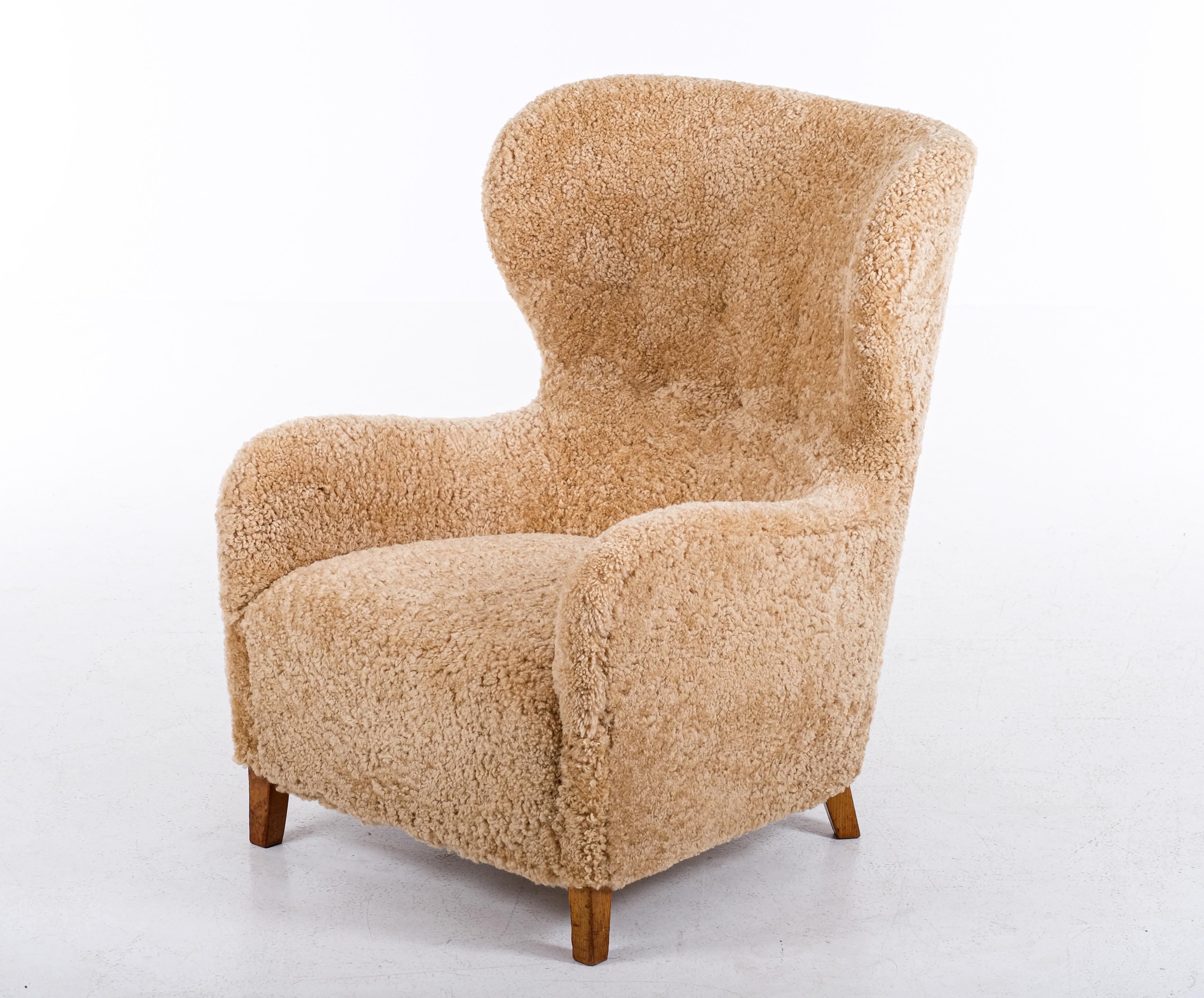 High-back Danish armchair in newly upholstered sheepskin, honey colored. Produced in Denmark during the 1940s. Excellent condition.
 