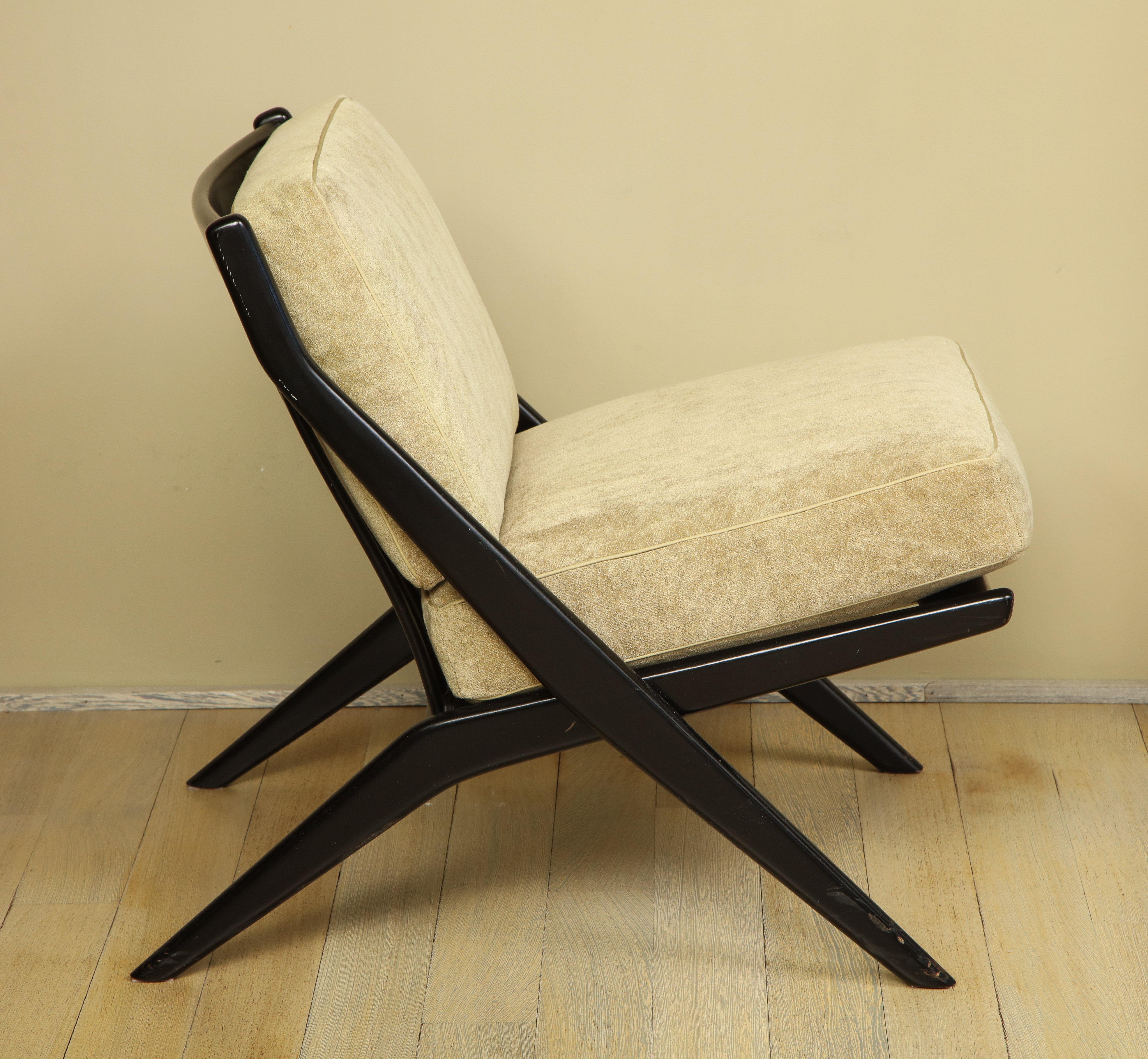 A single Scissor-style slipper chair with ebonized wood frame and removable seat and back cushions.  Made by Folke Ohlsson for Dux.  Sweden, circa 1960. Unsigned. two removable beige upholstered cushions.

Features wood frame with brass metal rod