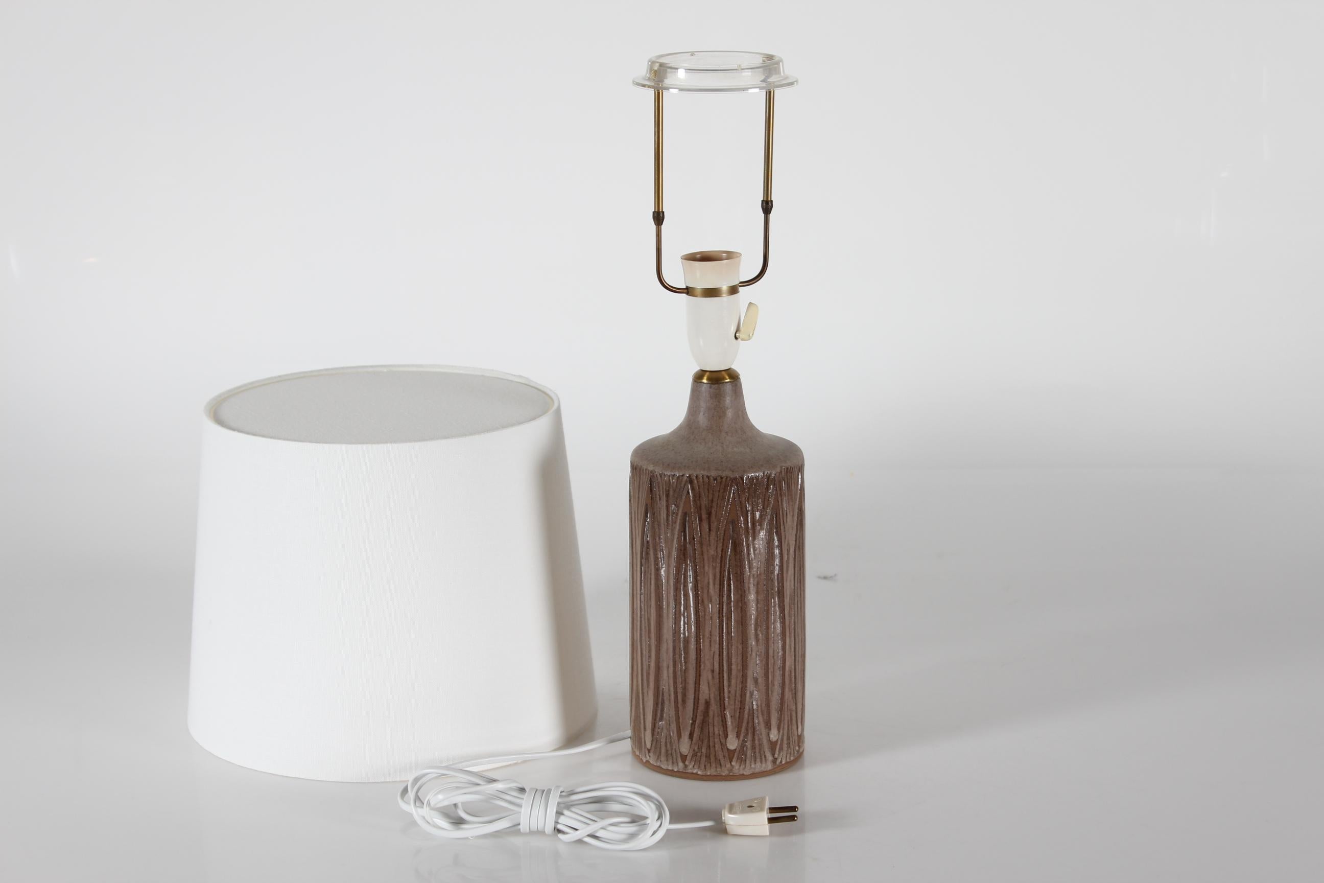 Lampe de table en grès du milieu du siècle, conçue et fabriquée par Einar Johansen dans les années 1960.

La lampe présente un motif cannelé incisé à la main en lignes verticales.
La glaçure brune claire et brillante, de couleur terre ou chocolat au