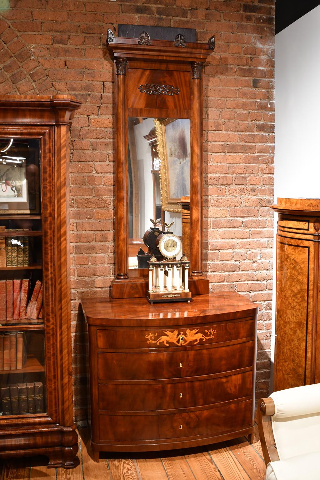 Una cassapanca o commode Impero molto raffinata con fronte ad arco che offre quattro cassetti su piedi affusolati nel miglior mogano cubano (Indie Occidentali) accoppiato a libro. Intarsi in legno di raso raffiguranti due sfingi decorano il cassetto