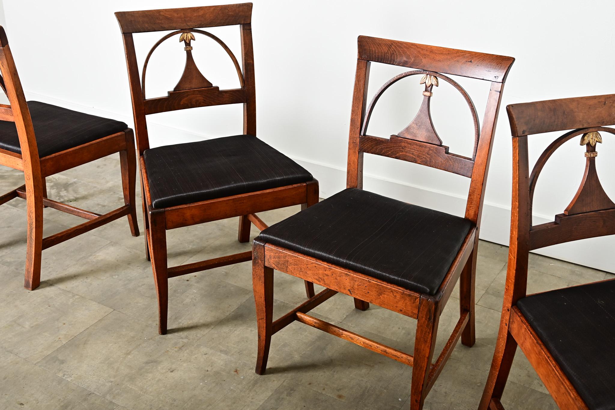 Un magnifico set di quattro sedie da pranzo in mogano della Danimarca del XIX secolo che riflette i gusti dell'Impero e del Biedermeier per un design evocativo, lussuoso e ricco di riferimenti storici. Gli schienali aperti e sobri sono