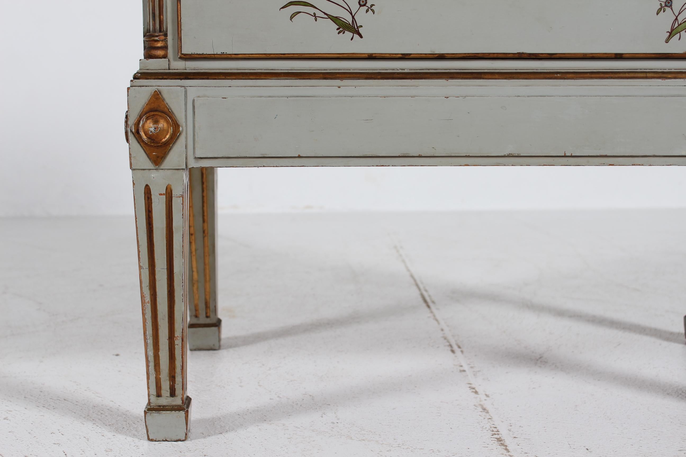 Cómoda de tres cajones ondulados de estilo imperio danés sobre patas altas de madera de pino maciza. Hecho a mano por un maestro carpintero danés en la década de 1930.

El arcón está decorado con pintura gris claro y dorado con flores pintadas a