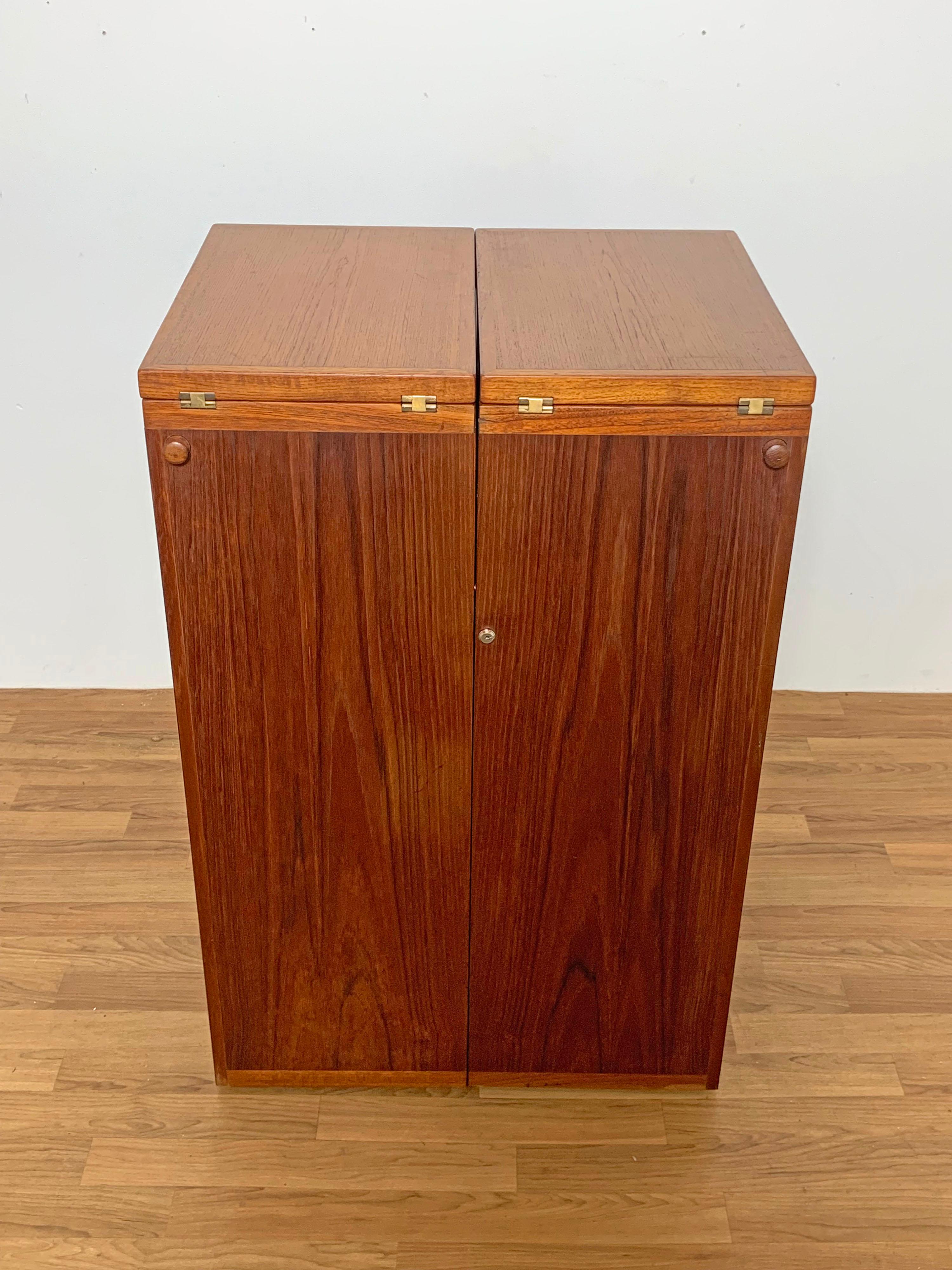 Danish teak folding bar cabinet by Reno Wahl Iversen for Dyrlund. Opens and expands to become a full service bar counter with black laminate surface for drinks.

Measures 23.25