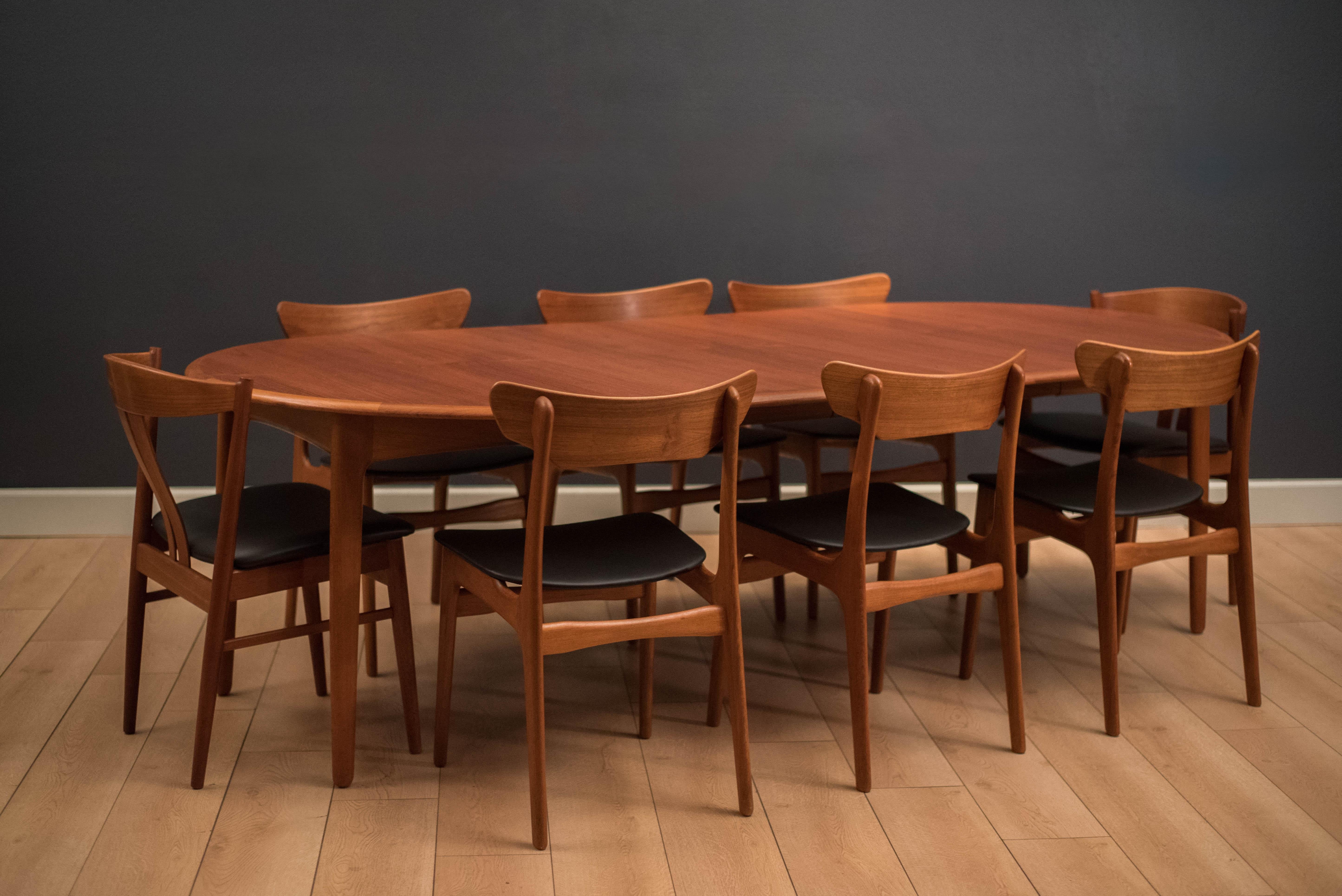 Vintage mid century round dining table designed by Svend Aage Madsen in teak. This piece features opposing solid teak edge banding and unique angled tapered legs. Includes two separate leaves that extend to an oval tabletop to allow more