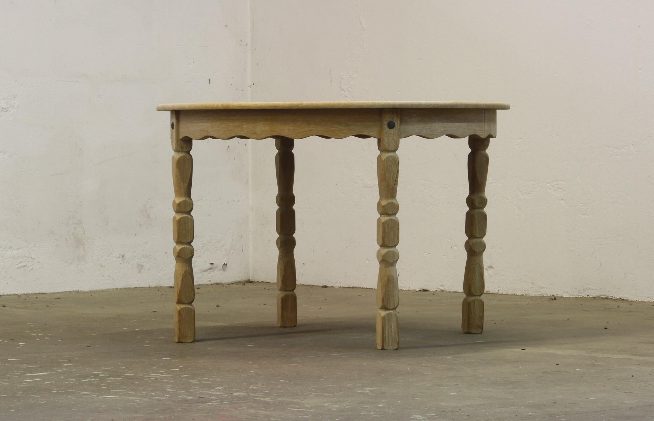 This vintage mid-century oak dining room, or kitchen, table captures the essence of Henning Kjærnulf's design philosophy, blending a bold brutalist aesthetic with refined danish craftsmanship. The intricate leg carvings harmonize beautifully with