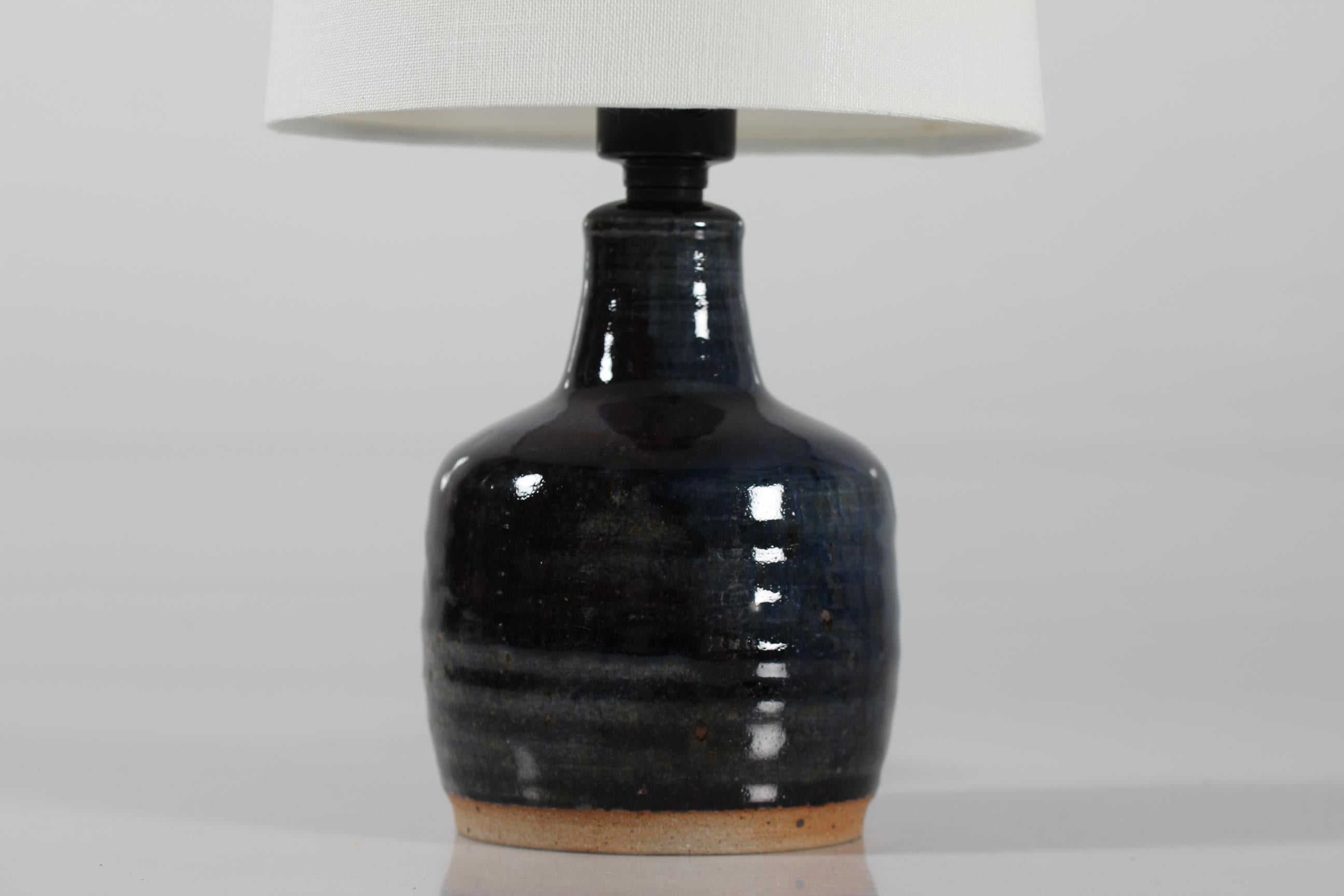 Stoneware bed side table lamp by Danish ceramist and glass artist Finn Lynggaard (1930-2011).
The lamp base is decorated with dark blue glossy glaze in different shades.

Included is a new lamp shade designed and made in Denmark. It's made of woven