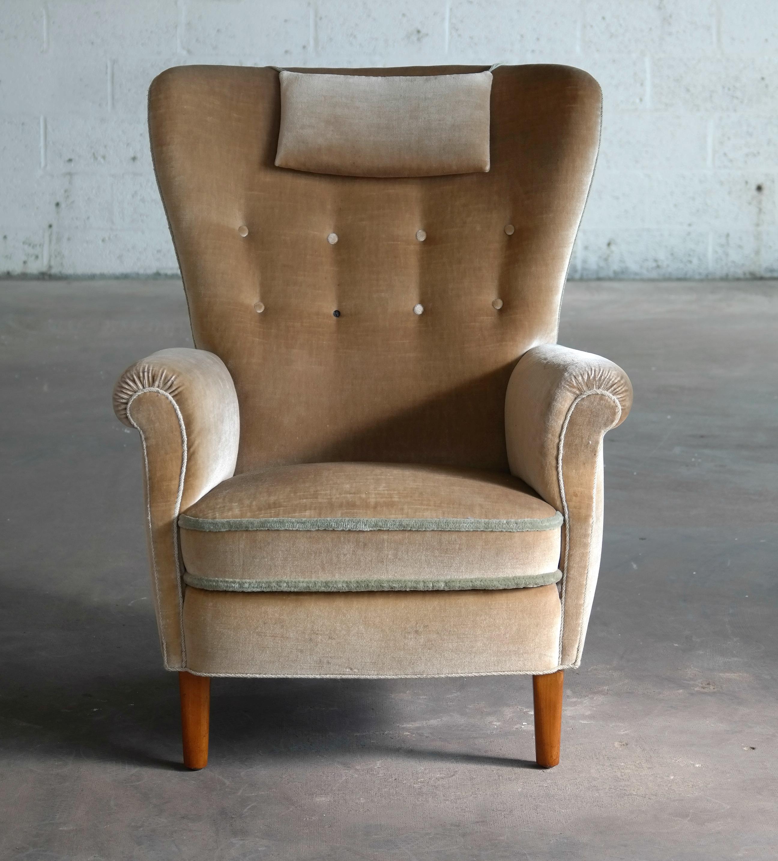 Eleganter Loungesessel mit hoher Rückenlehne im Stil von Fritz Hansen und Flemming Lassen. Das gefederte Sitzkissen ist noch mit dem ursprünglichen Mohair-Samt bezogen. Wir haben den Stoff gereinigt und obwohl er noch brauchbar ist:: zeigt er