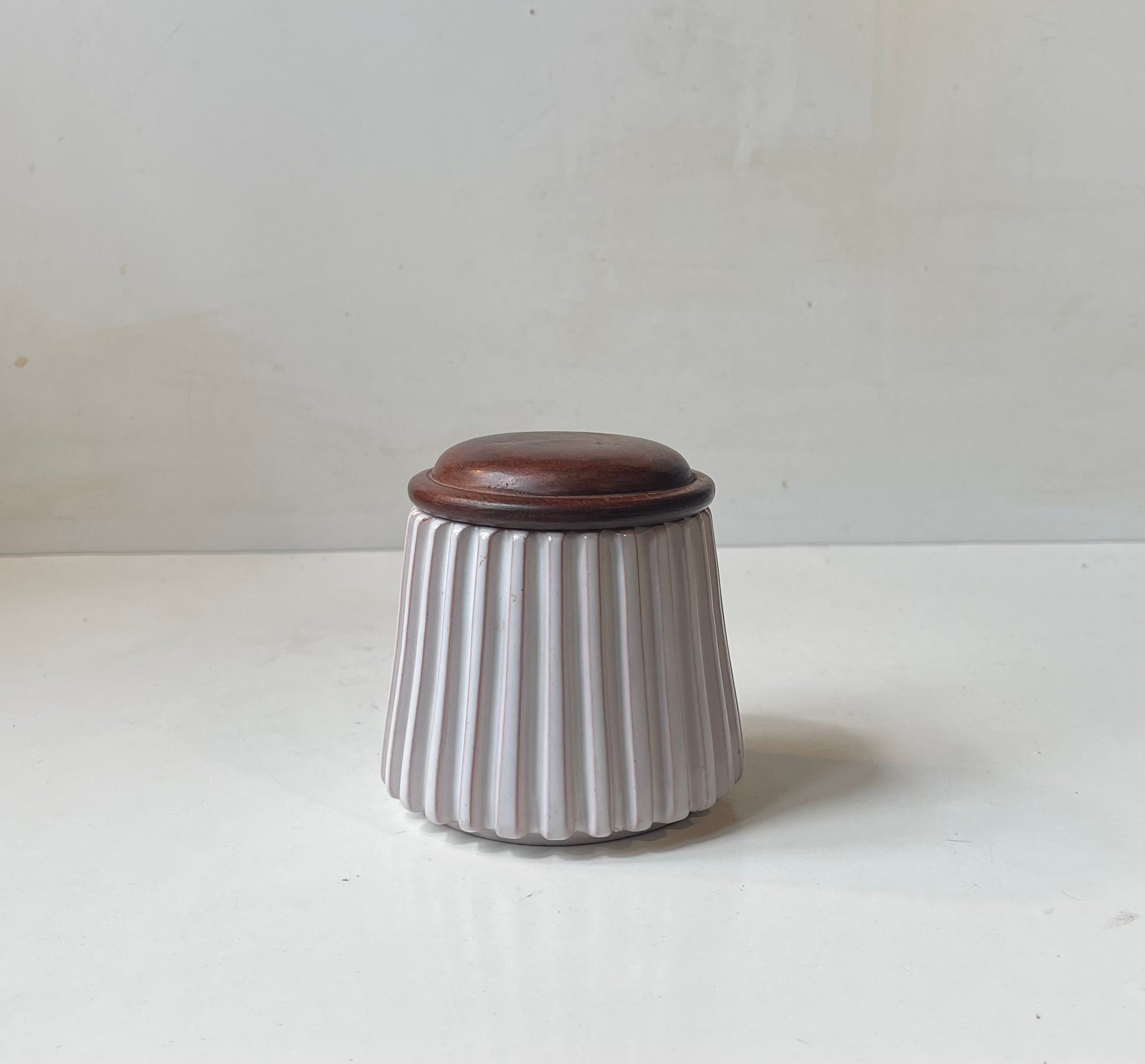 Vaso o ciotola con coperchio in ceramica scanalata e smaltata di bianco, disegnata dai due fratelli Esben & Lauge e prodotta nel loro laboratorio di Eslau in Danimarca alla fine degli anni Cinquanta. Lo stile di questo pezzo ricorda molto le opere