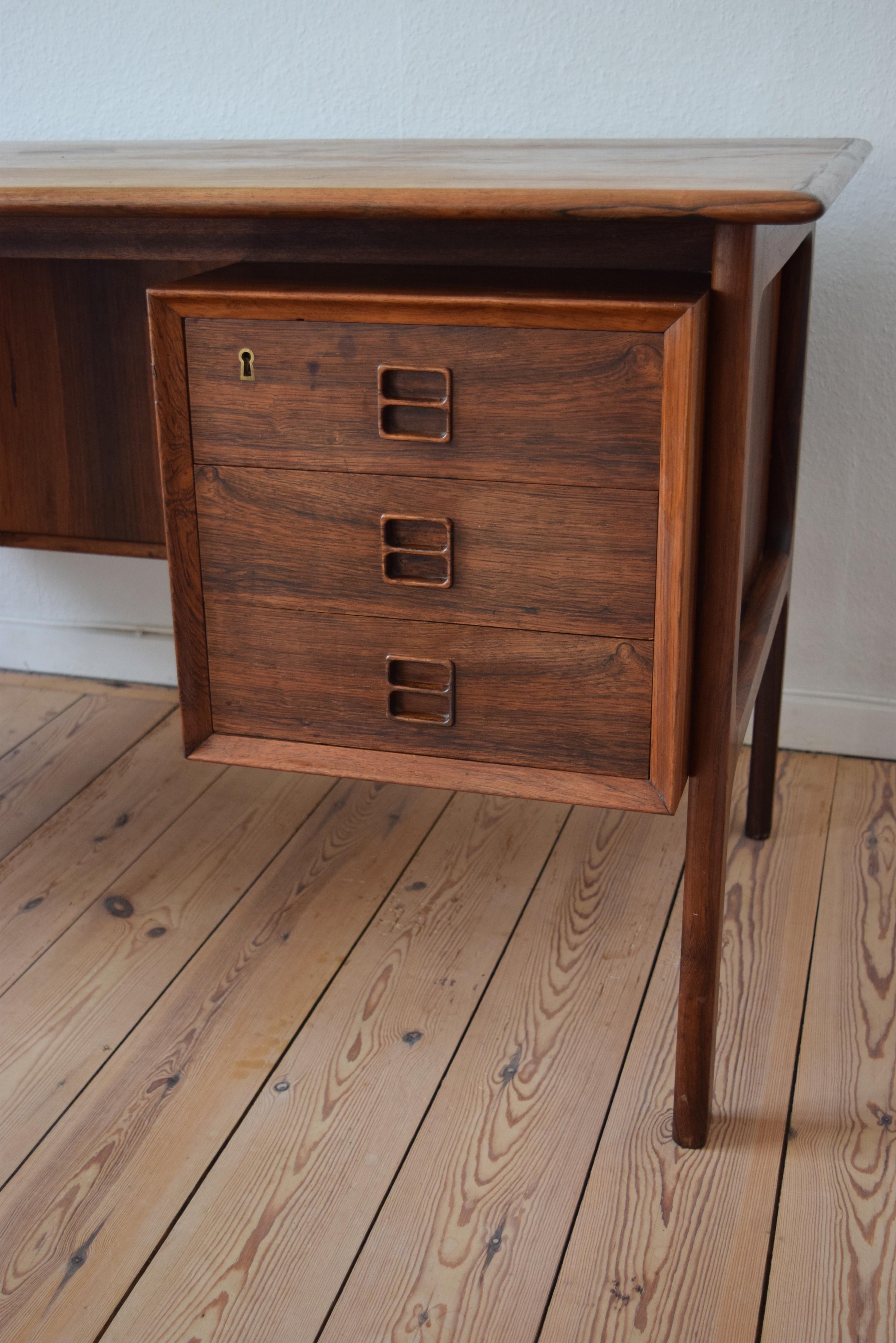 Brazilian rosewood executive desk designed by Arne Vodder for Sibast Møbler in the 1960s. This freestanding desk features a floating top with six drawers on the front, two lockable (key included). Three bookcase sections on the rear with bevelled