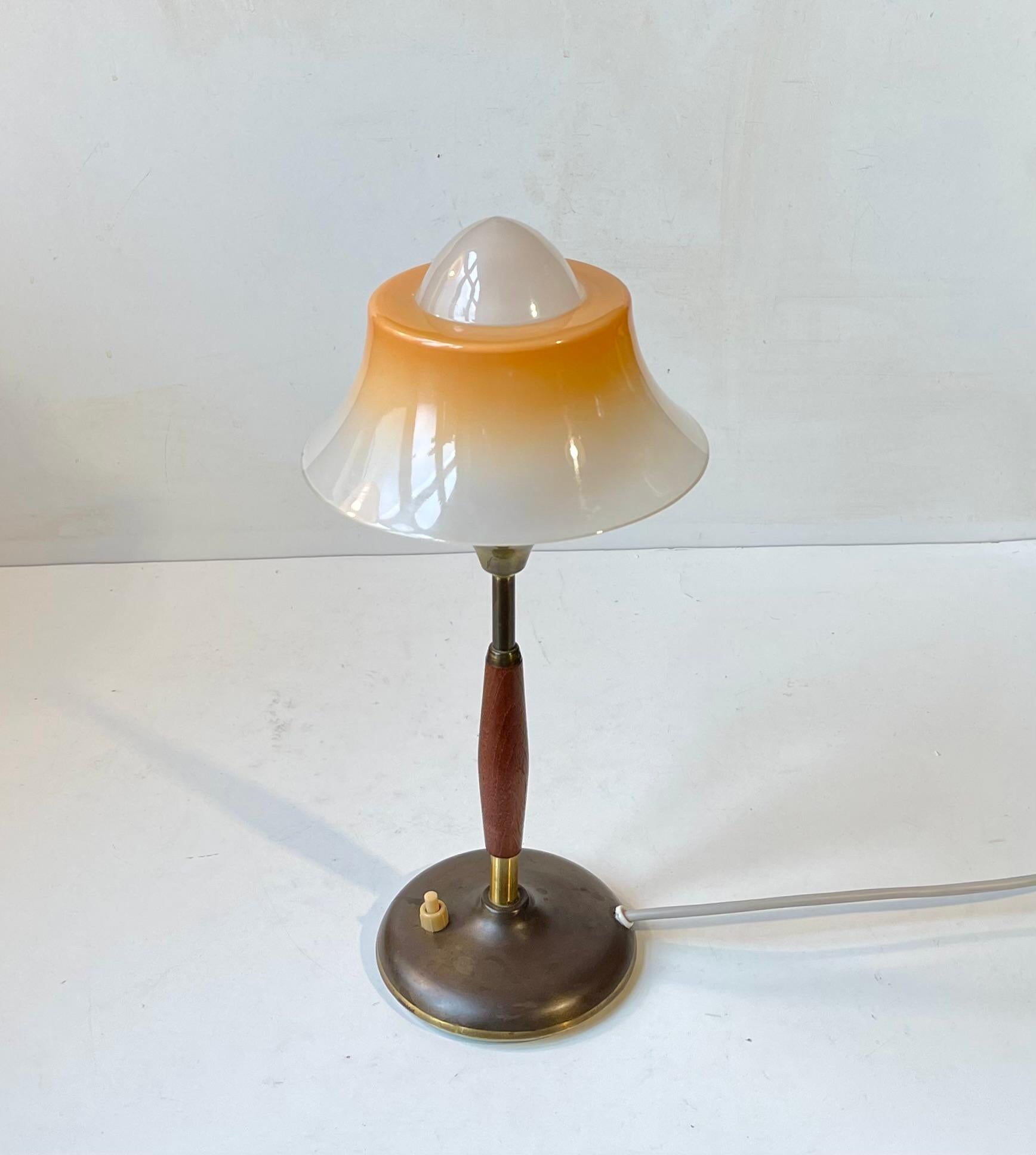 Danish Art Deco styled desk lamp designed by Fog and Mørup during the 1930s. It features a brass base and rod set with solid teak. The iconic single layered, partially painted vaseline glass top shade resembles a fried egg - hence its name. This