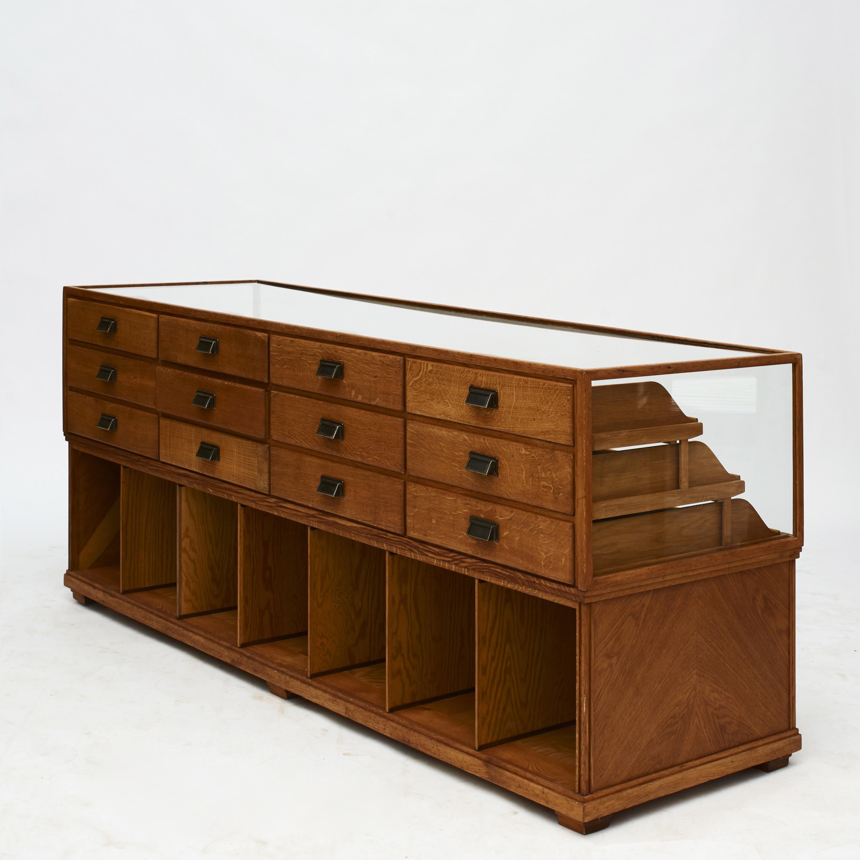 A freestanding counter made in during the 1930s in Denmark. It features an oak frame with a glass top and glass partly covering front and sides. Drawers with original metal handles.

This is a quality shop counter, well suited for displaying