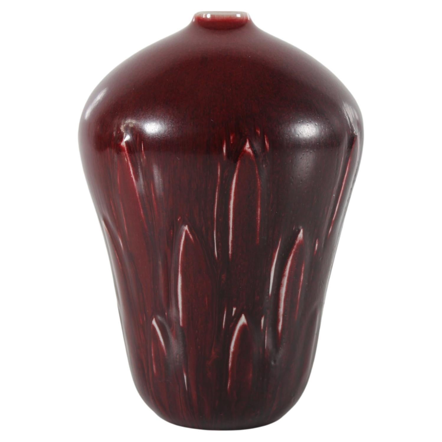 Grand vase du céramiste danois Gerd Bøgelund (1923-1987) pour Royal Copenhagen Denmark. 
Il est fabriqué en grès dans les années 1960. 

Le vase est décoré d'une ornementation de feuilles incisées et recouvert d'une glaçure sang-de-bœuf.

Enseigne