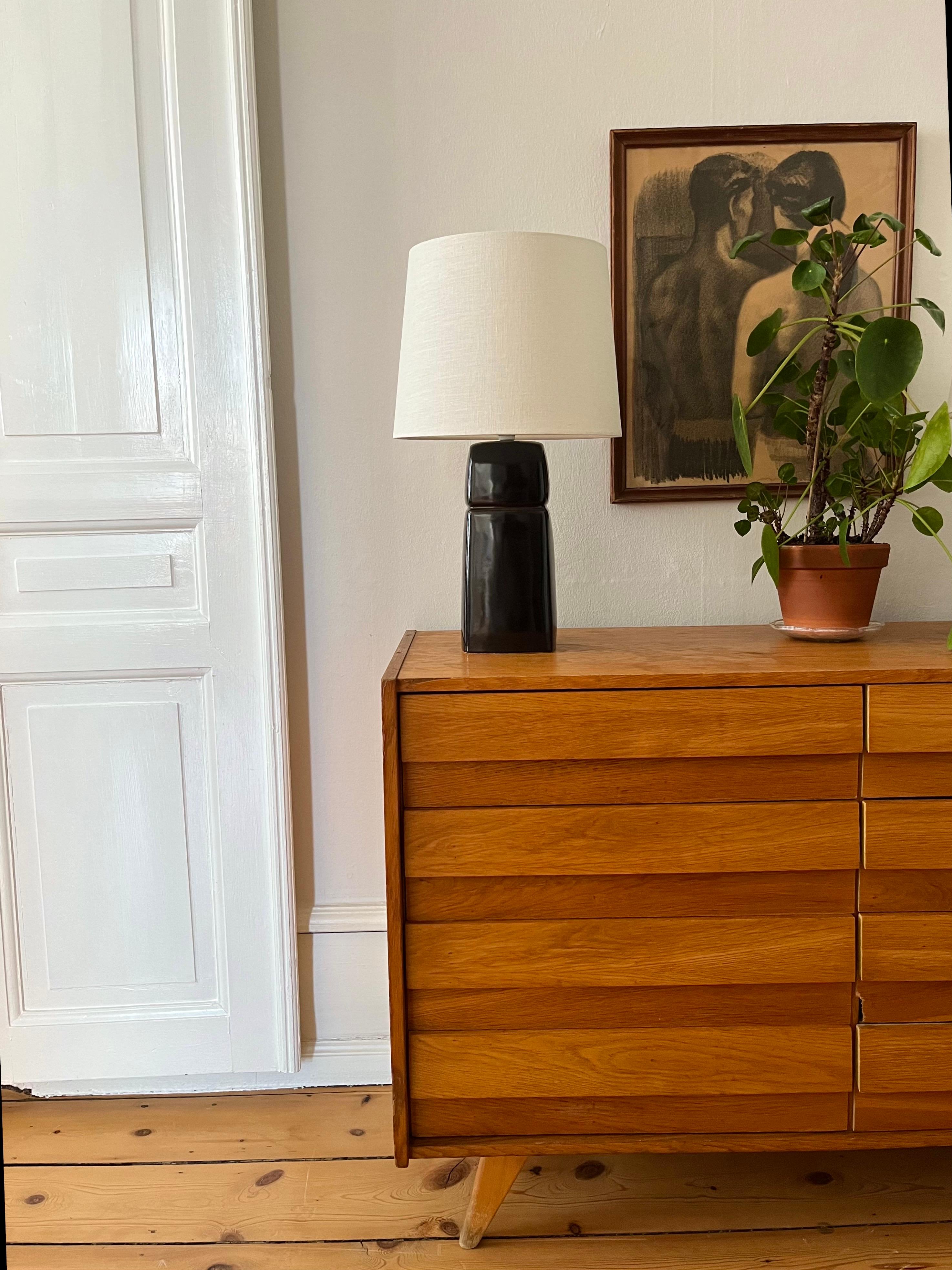 Danish Gerd Hiort Petersen Modernist Ceramic Table Lamp, 1960s

Handmade and hand-decorated Danish ceramic table lamp by artist Gerd Hiort Petersen from the 1960s. 
Blackish warm dark brown glazed ceramic in a soft cornered rectangular shape with