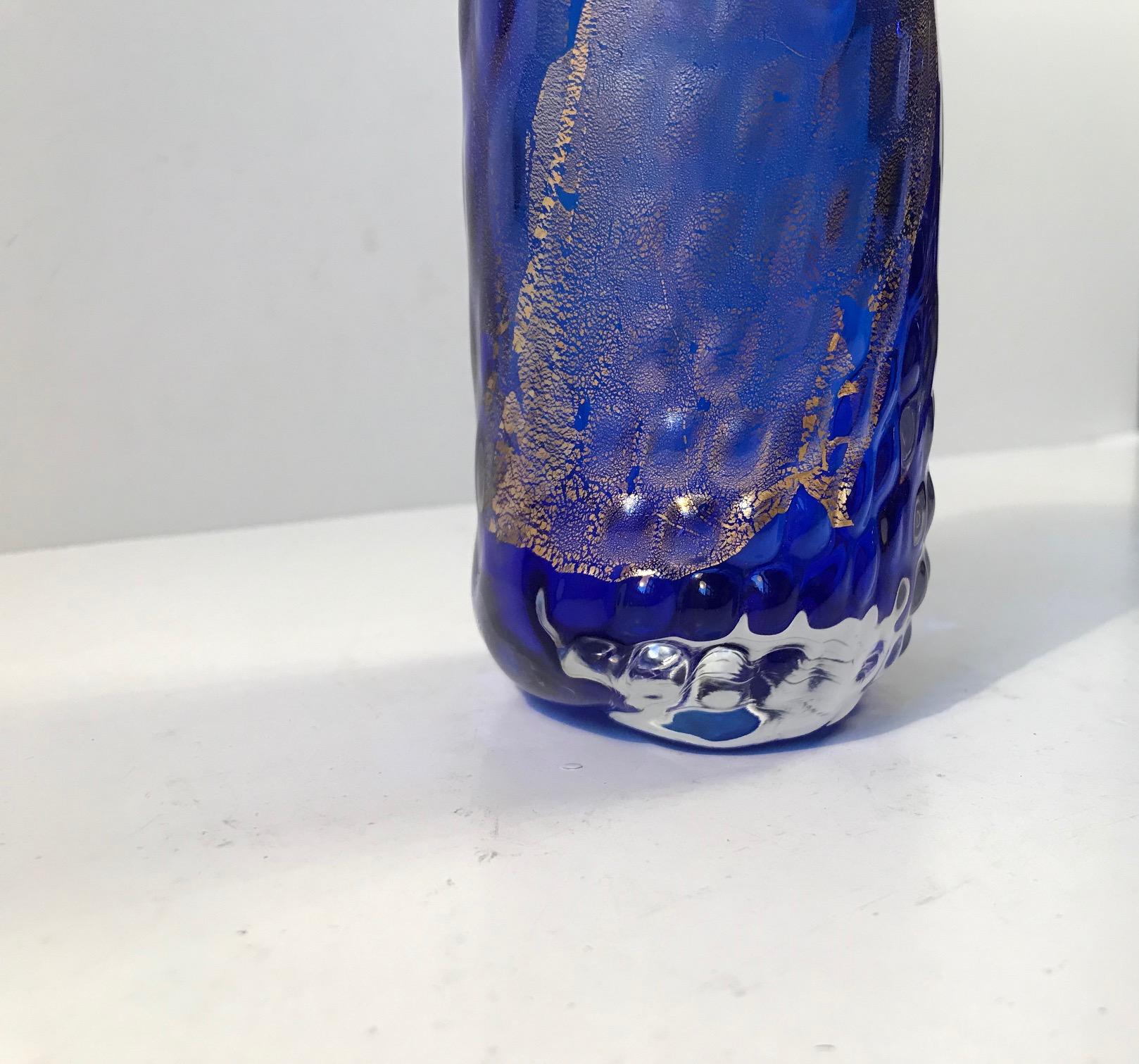 Blue glass vase decorated and infused with 24-carat gold dust. Its a unique piece and it was created during the 1990s by Tchai Munch who owns a workshop in Ebeltoft, Denmark. During the 1980s, 1990s and 00s she has a close relationship with Finn