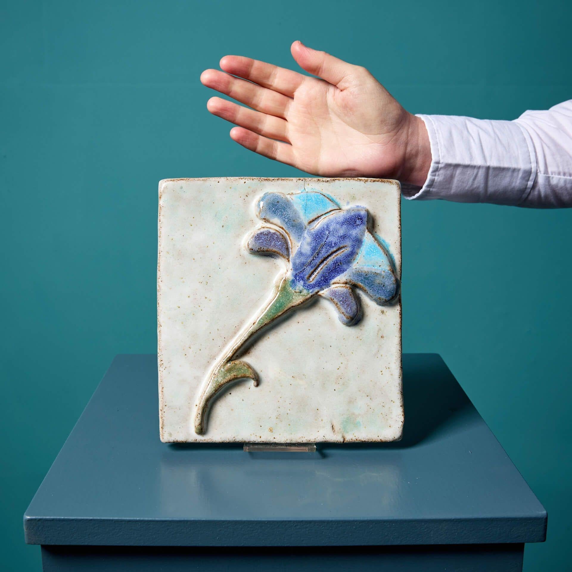 Carreau ou plaque murale en terre cuite émaillée, d'origine danoise, représentant une seule fleur bleue. Bien que son auteur soit inconnu, cette pièce est considérée comme étant dans le style de l'artiste danois Erik Nyholm, connu pour ses plaques