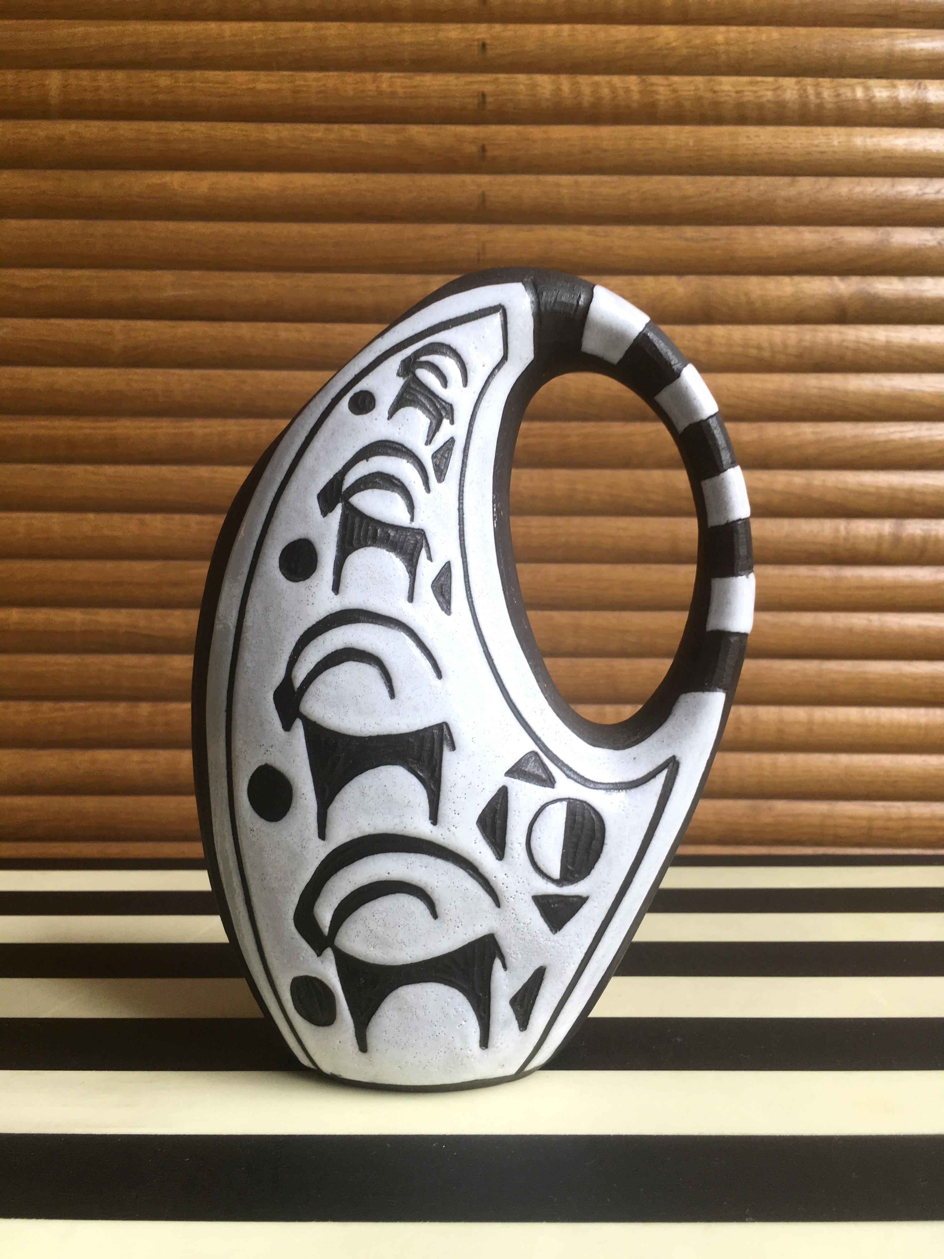 Beautiful handmade Danish modernist ceramic pitcher vase from the Tribal series by ceramic artist Marianne Starck (1931-2007). Smooth rounded shapes with striped handle. White glaze with hand-carved stylized animal decor on raw anthracite clay. Made