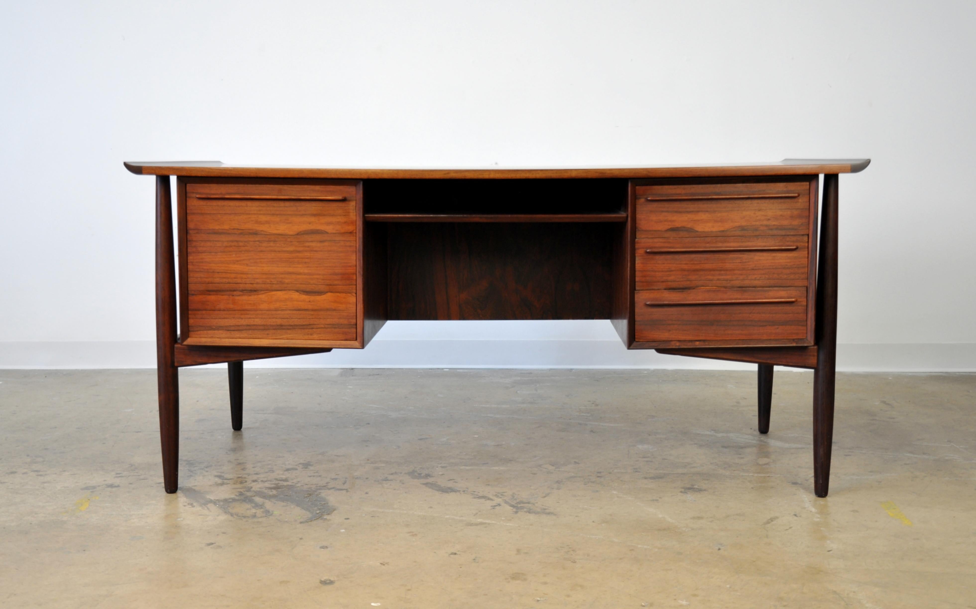 A stunning example of a vintage midcentury Danish modern executive desk or large vanity table by H.P. Hansen, dating from the 1960s. Of gleaming Brazilian rosewood, the writing table features a curved top over three drawers, a fixed shelf and a