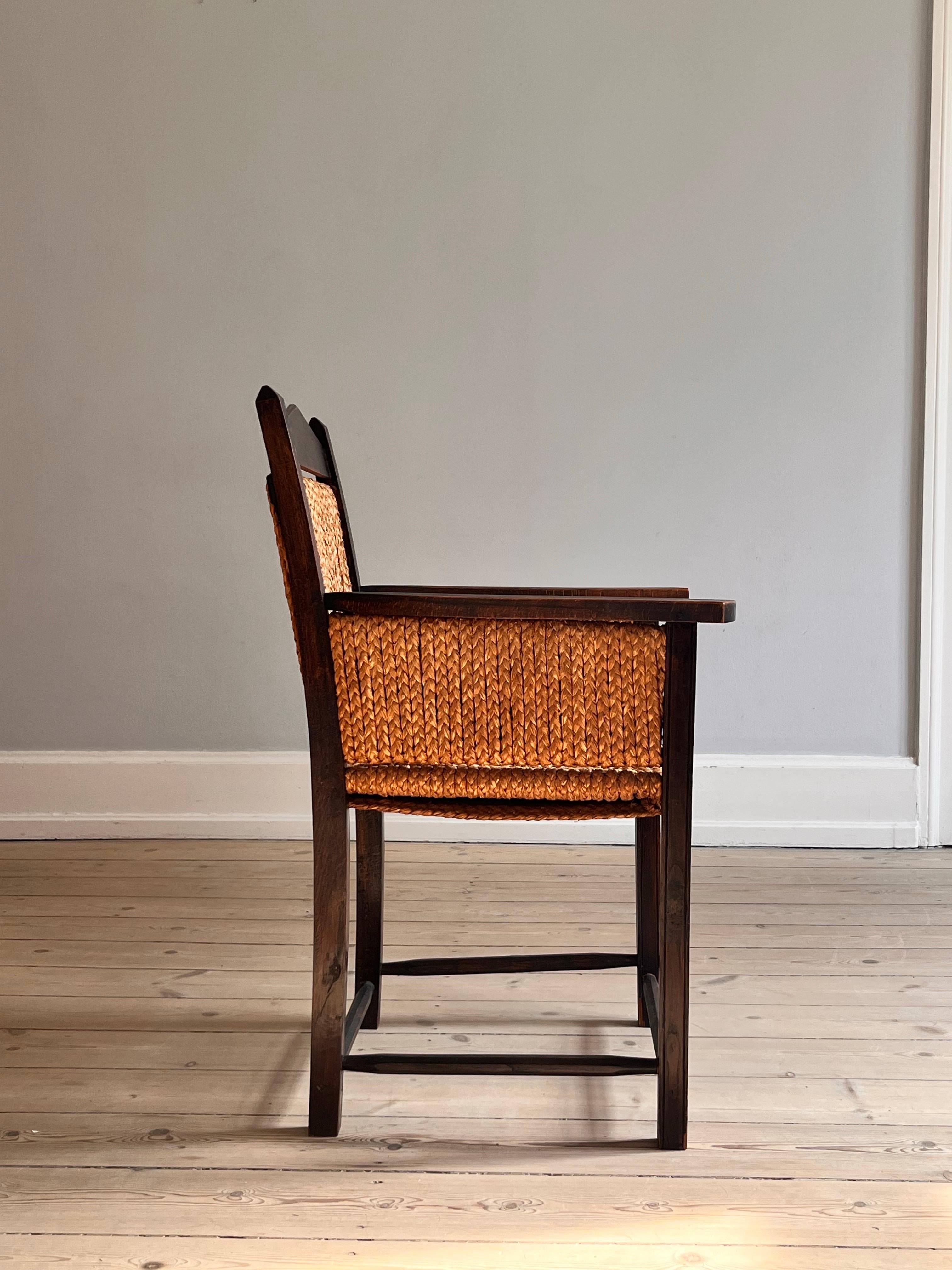 Poltrona danese intrecciata a mano in corda e faggio degli anni '60 circa. 

La sedia è splendidamente patinata e realizzata in legno di faggio tinto scuro e con corda intrecciata a mano nello schienale, nella seduta e sui lati sotto i braccioli.