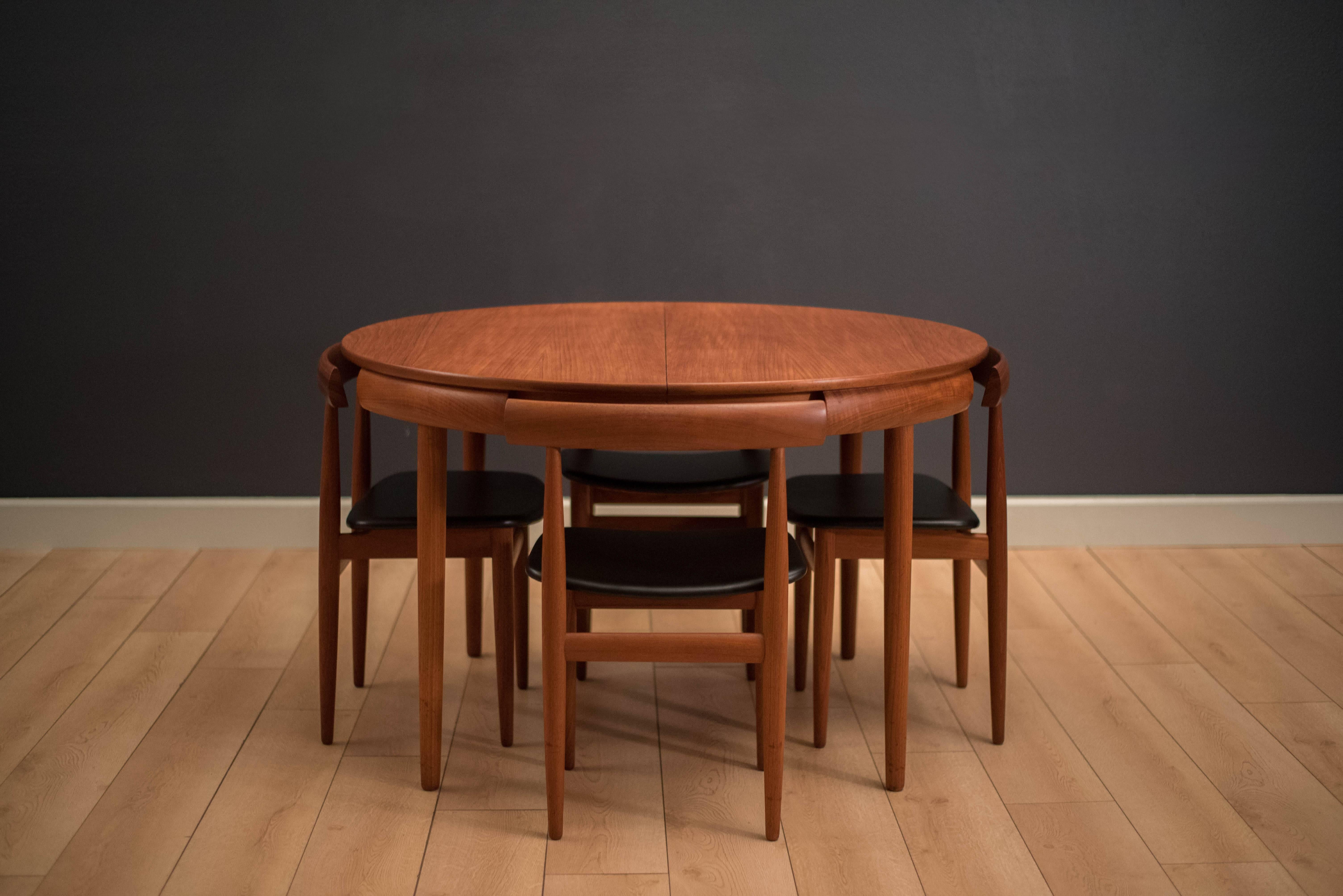 Mid Century round dining set designed by Hans Olsen for Frem Rojle in teak. This compact set includes four chairs that cleverly nest into the table. These dining chairs are the four legged version and seats have been newly reupholstered in black