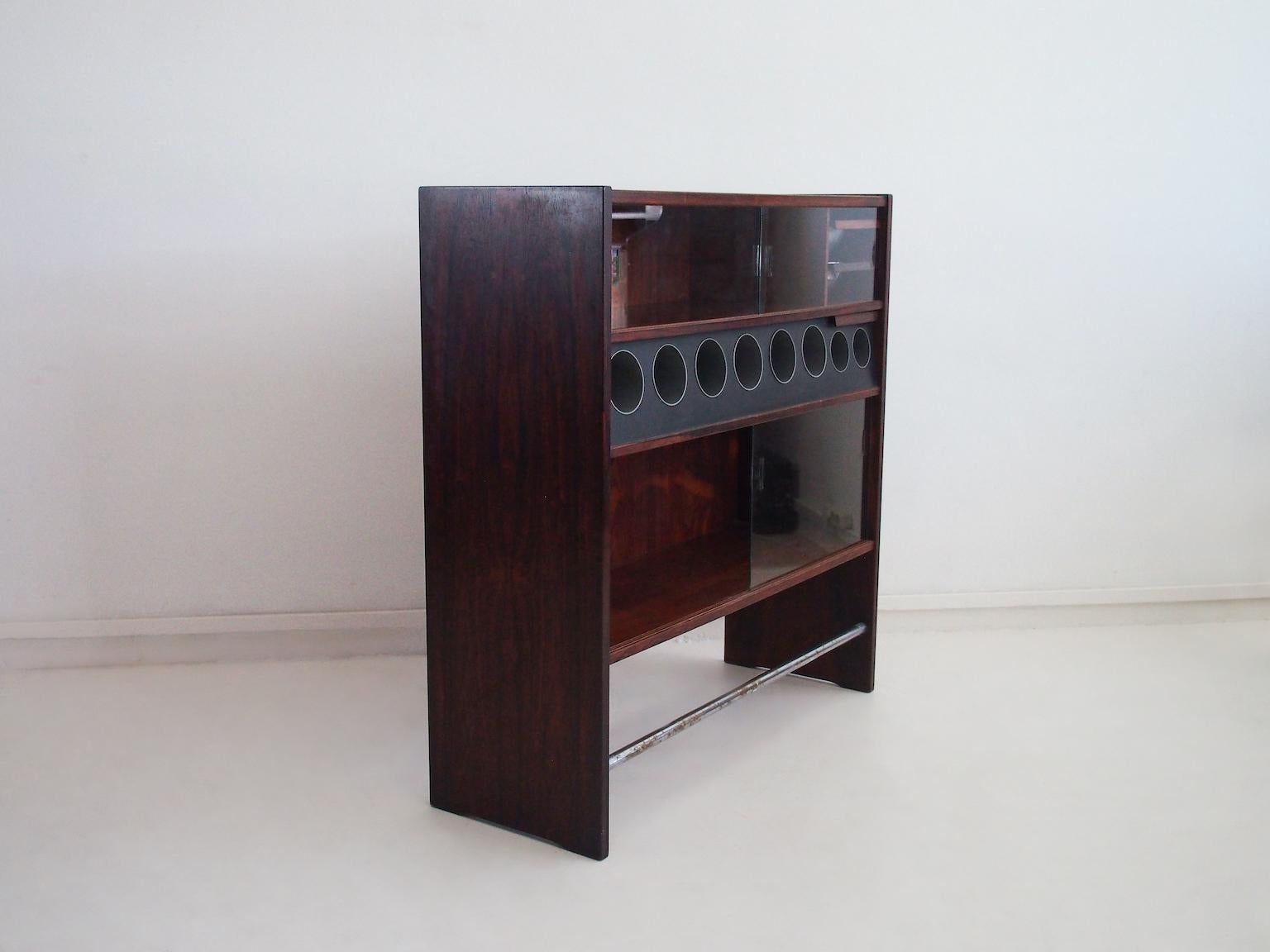 Rectangular hardwood dry bar designed by Erik Buch and made in Denmark circa 1960s. Front with eight bottle racks and two wine racks, two sliding glass doors with shelves behind and dishes for ice cubes on the upper part. There is another shelf on