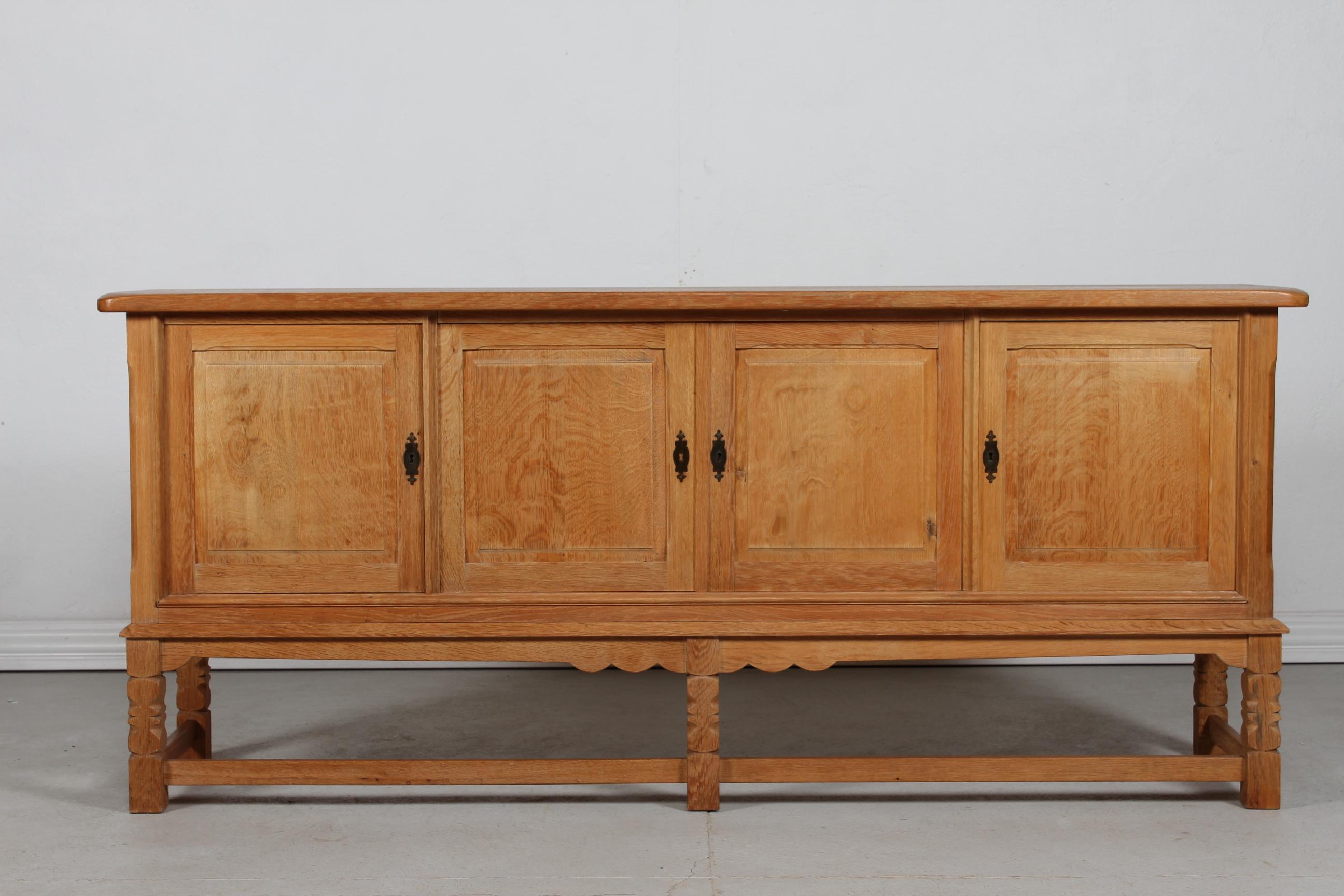 Long sideboard attr. to designer Henning Kjærnulf and most likely manufactured by the Danish company Nyrup Møbelfabrik/ EG Furniture, Denmark in the 1970s.

The country style sideboard is made of solid- and veneer oak and has four raised panel doors