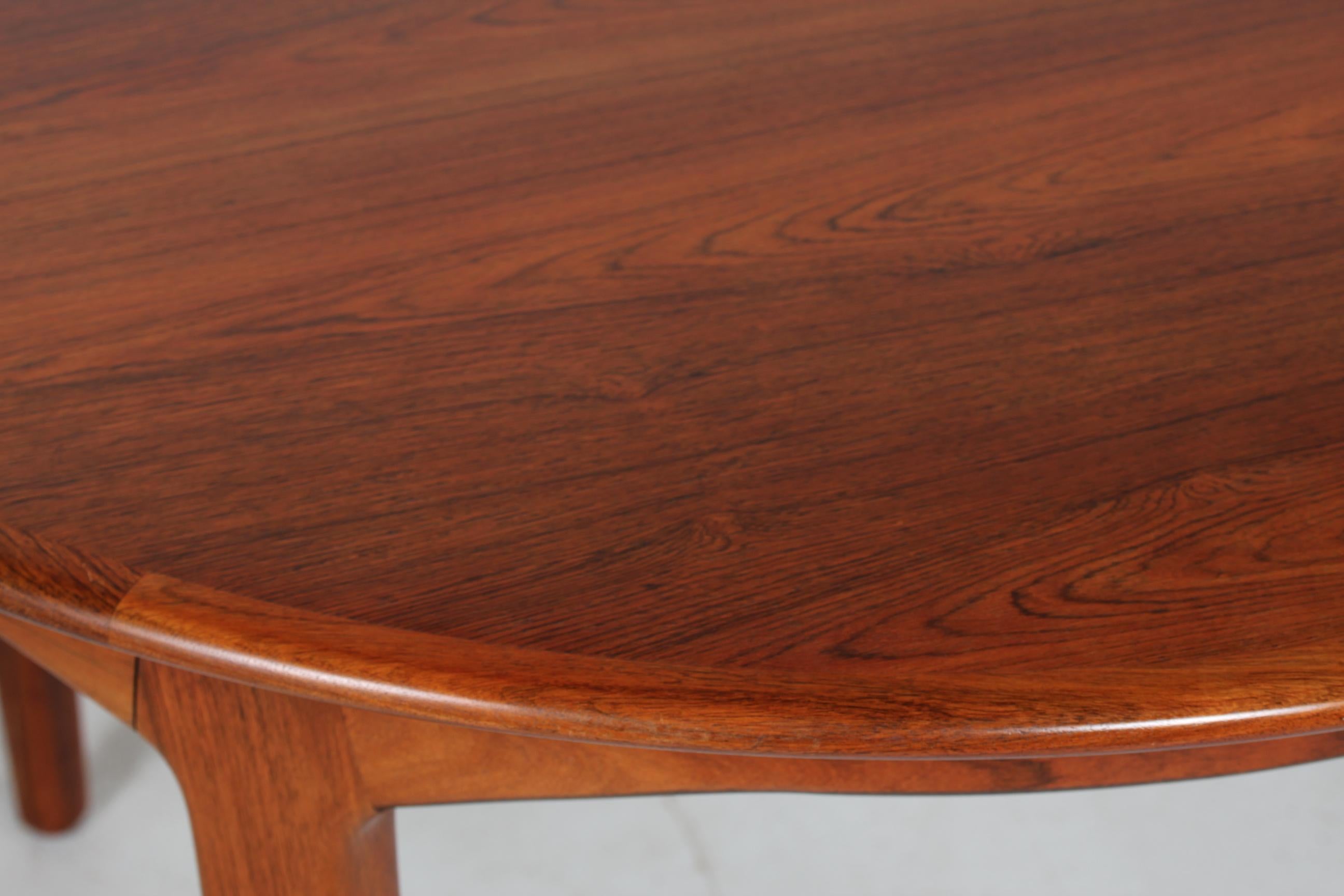 Danish vintage Henning Kjærnulf large round dining table model 62 manufactured by Sorø Stolefabrik, Denmark

The table is made of solid rosewood and rosewood veneer and can be extended by 2 extra leaves. 
One of the leaves has a frame underneath.