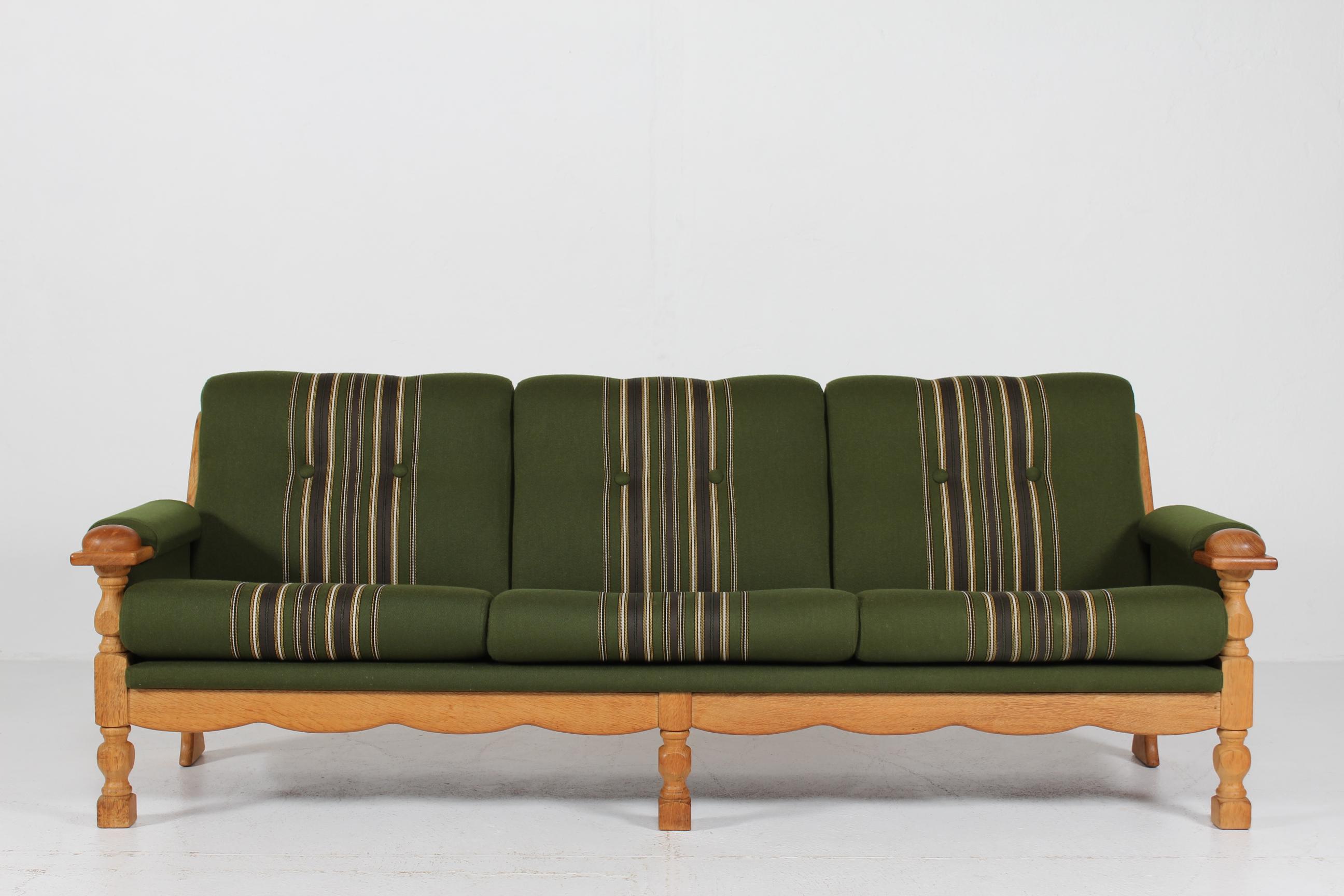 Danish vintage sofa designed by Henning Kjærnulf and manufactured in Denmark by EG Møbler.
The frame and armrests are made of turned and carved solid oak upholstered with the original dark green striped wool. The seat cushions are loose and can be