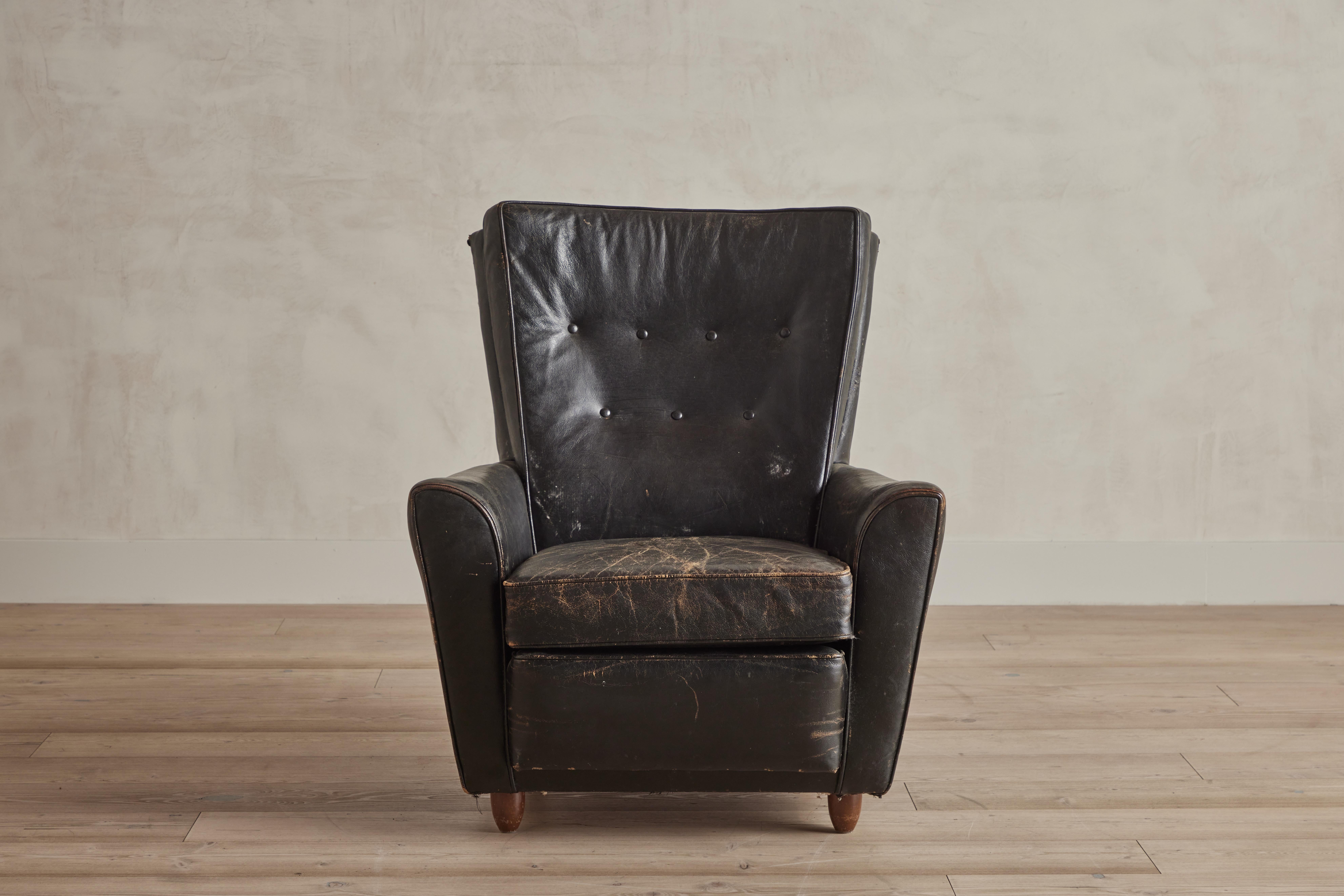 Midcentury black leather high back armchair. Heavy wear on leather that is consistent with age and use. Denmark 1960.