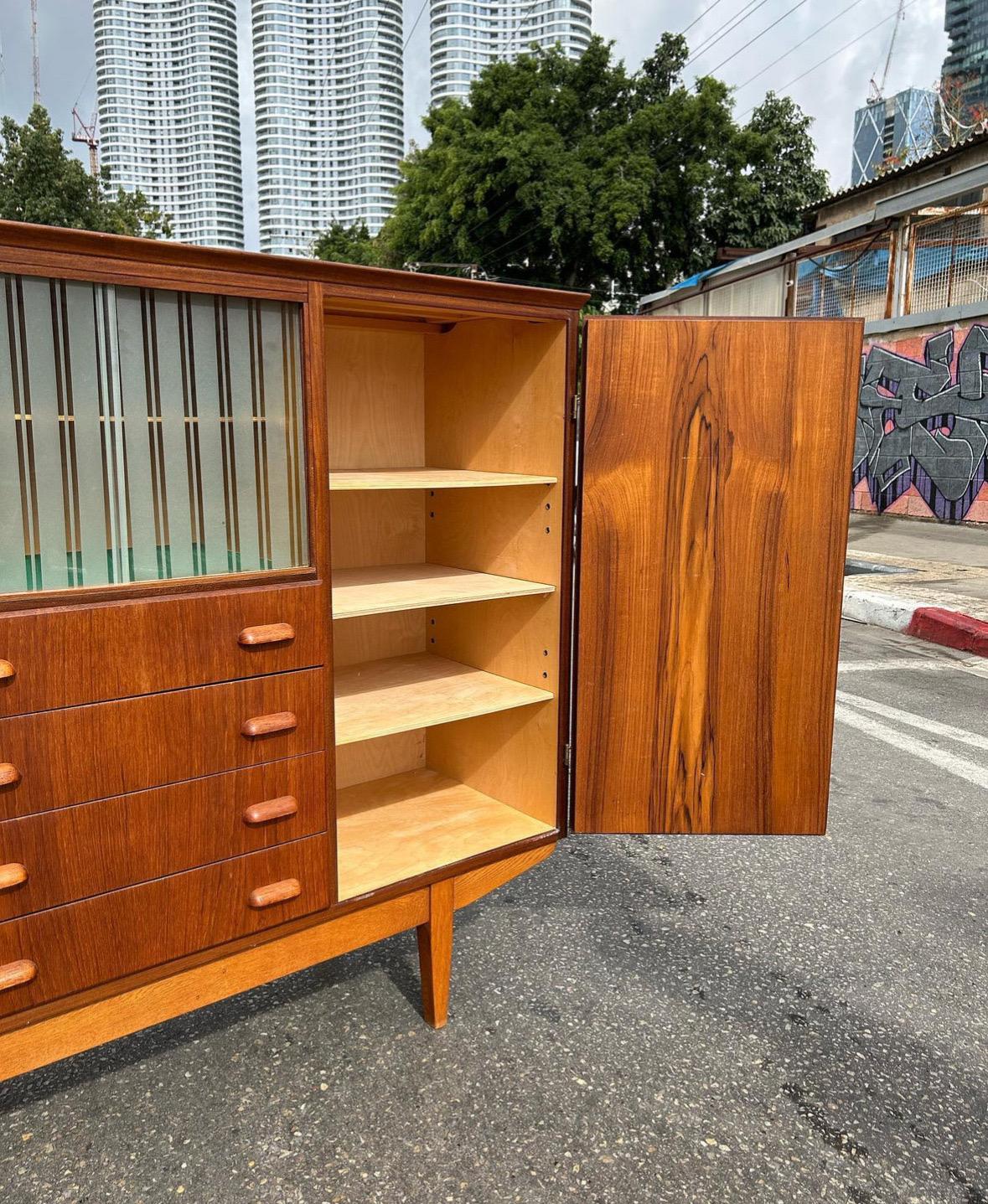 This Midcentury Modern Danish highboard from the 1960s exemplifies the refined craftsmanship and functional elegance for which Danish design is renowned. Constructed from warm teak with contrasting oak details, this highboard combines clean lines