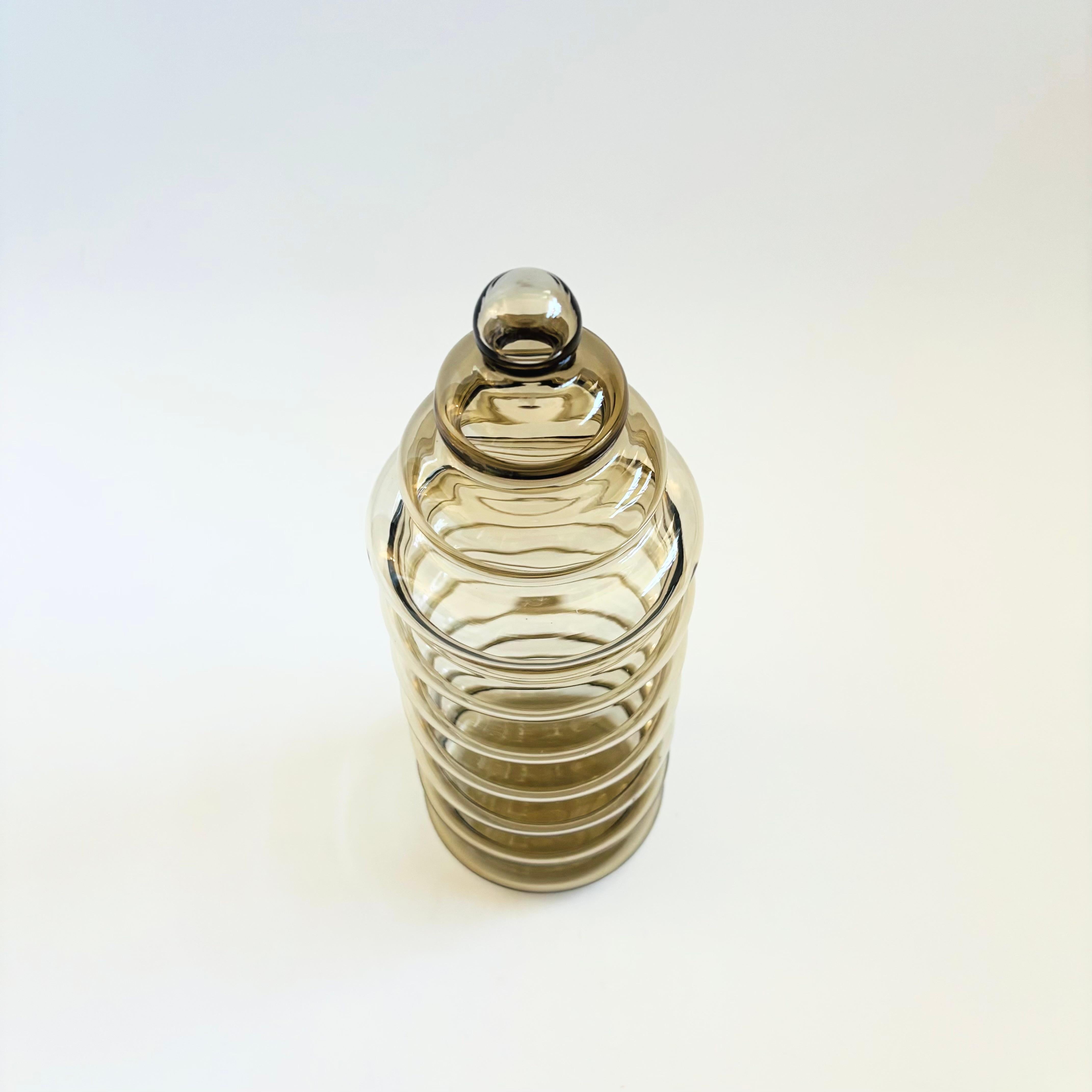 Un barattolo da farmacia d'epoca in vetro Holmegaard Primula in un caldo vetro grigio chiaro. Disegnato da Jacob Bang per Holmegaard. Un grande design scultoreo di anelli impilati con un coperchio a forma di cono. 2 sono disponibili in vendita